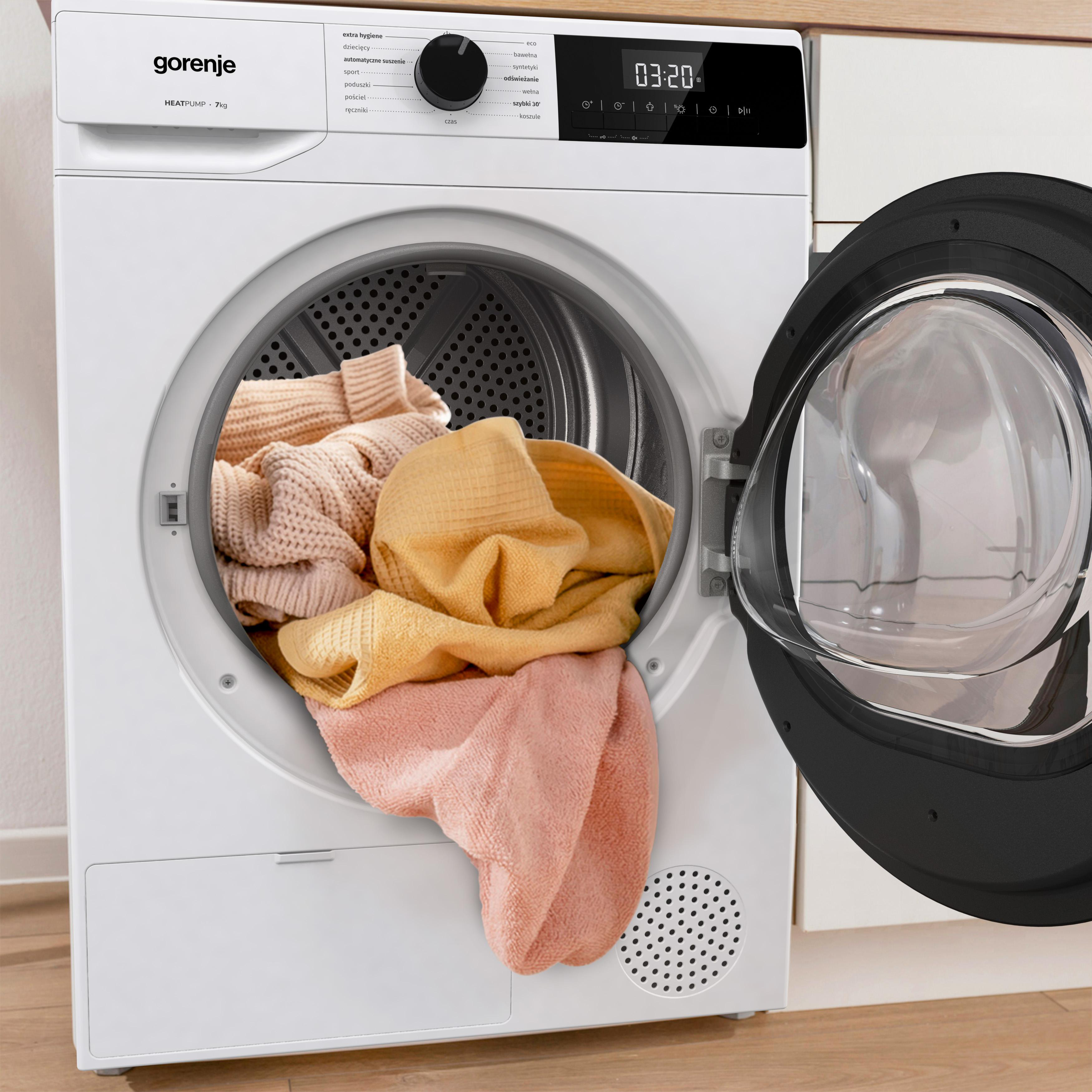 Ein weißer Wäschetrockner mit offener Tür, gefüllt mit Kleidung in Pastellfarben.
