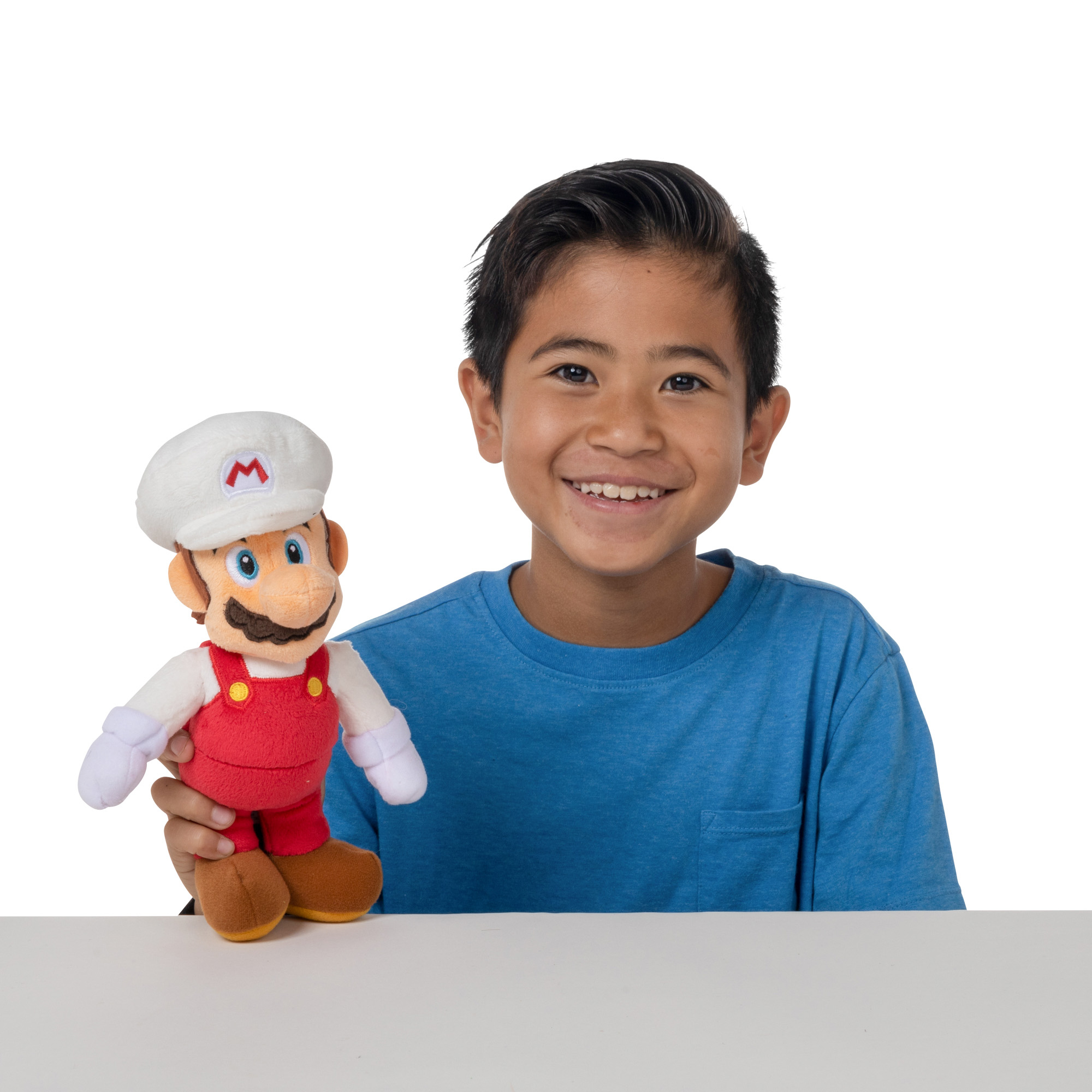 Ein Junge in einem blauen T-Shirt hält eine Mario-Puppe mit weißer Mütze und rotem Latzhose.