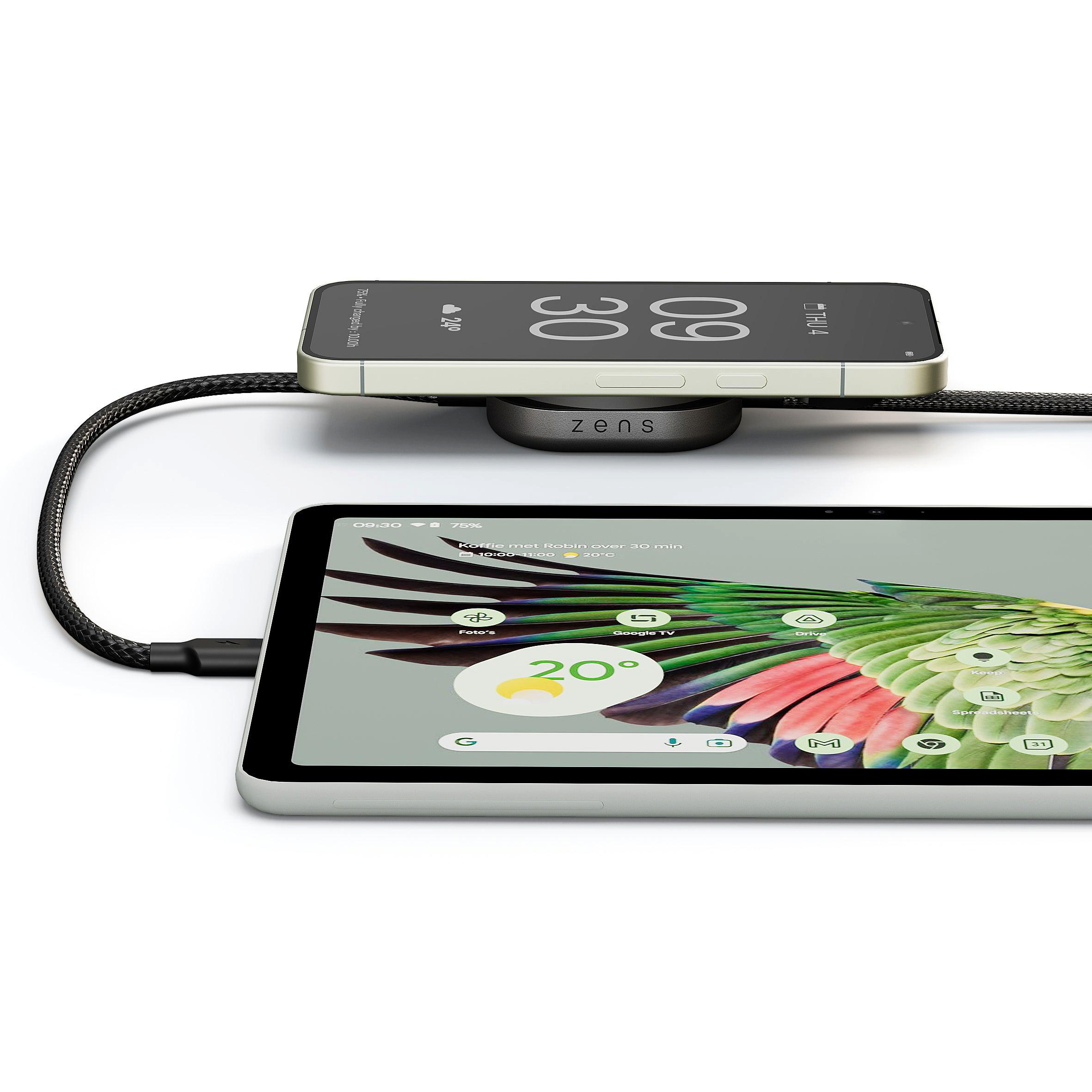 Ein Smartphone lädt auf einem Zens-Ladegerät, ein Tablet liegt daneben.