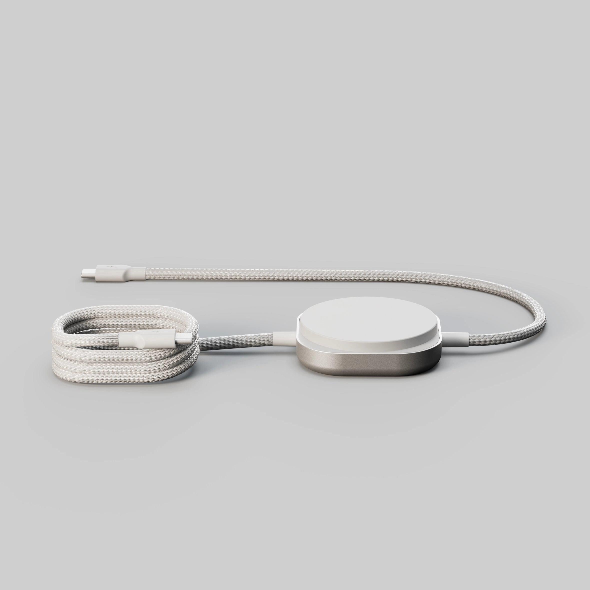 Ein weißes und silbernes Ladekabel mit einem runden Adapter, auf einem grauen Hintergrund.