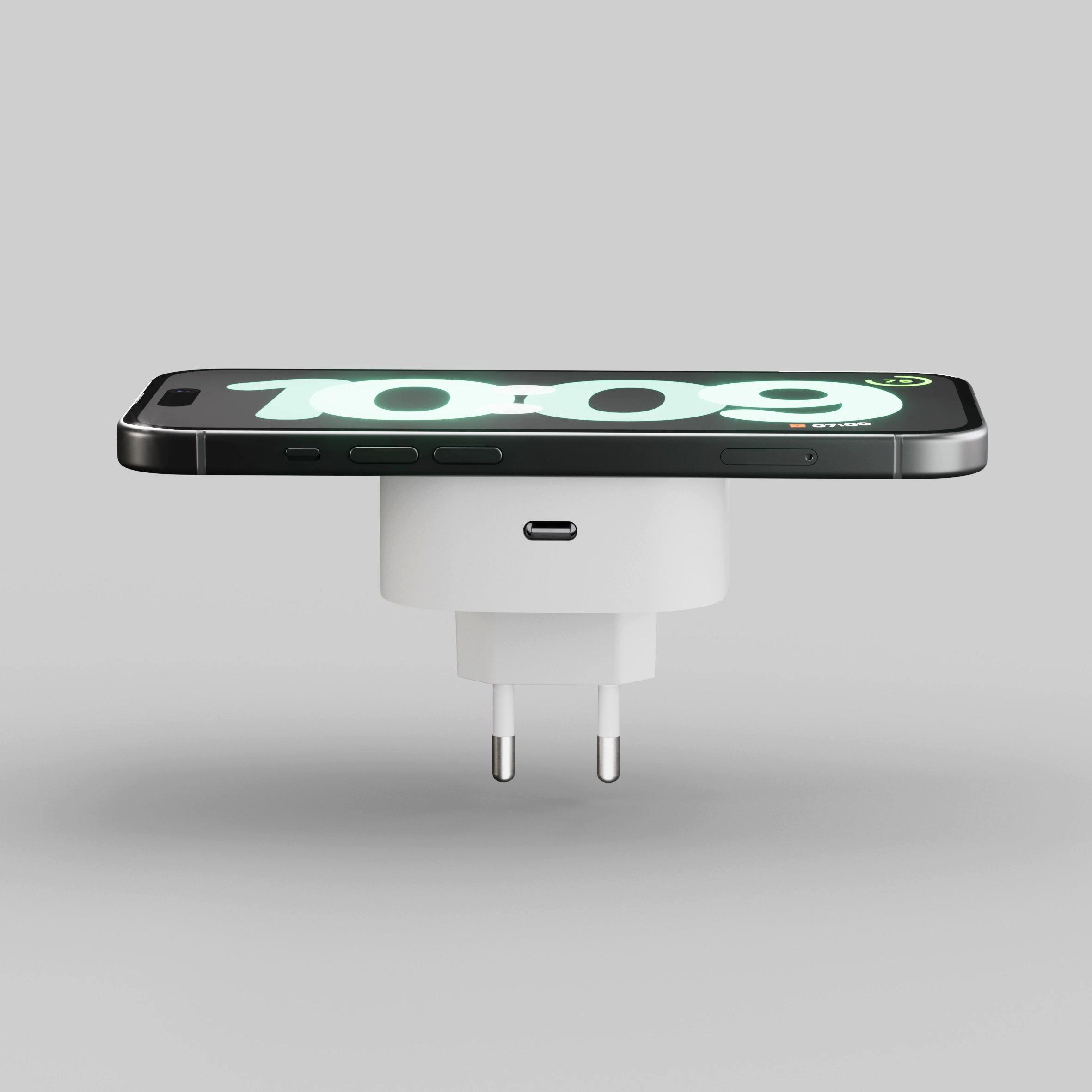 Ein schwarzes Smartphone lädt auf einem weißen Ladegerät mit zwei Pins.