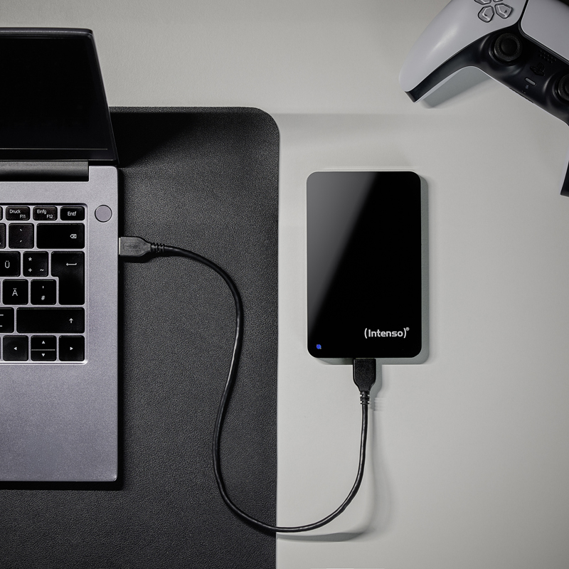 Ein Laptop ist über USB mit einer externen Festplatte verbunden. Ein Gamecontroller liegt daneben.