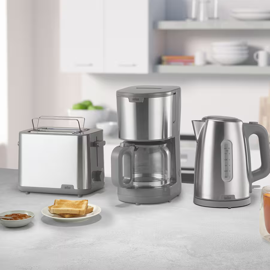 Toster, ekspres do kawy i czajnik na blacie z tostami i dżemem.