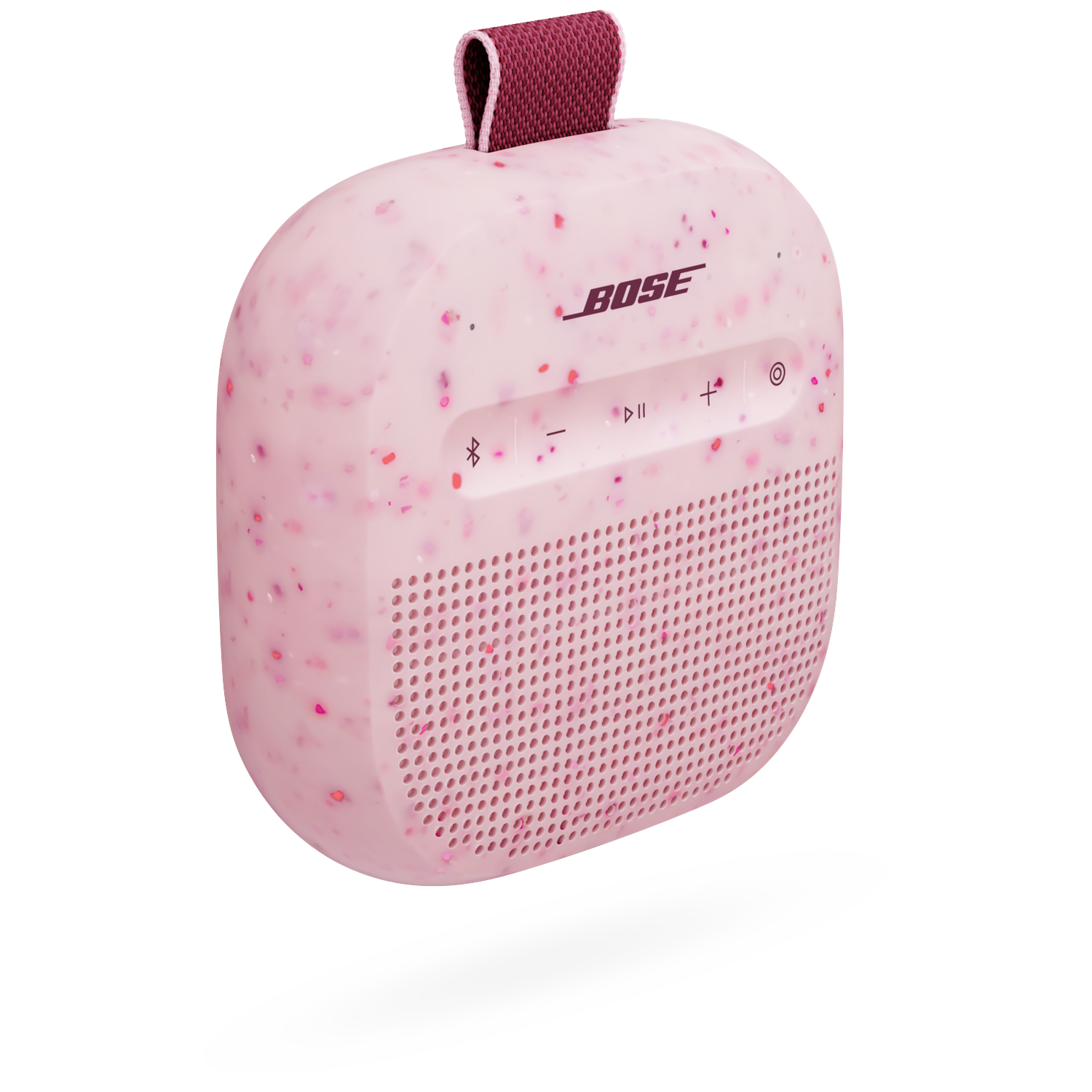 Een roze Bose SoundLink Micro Bluetooth-speaker met rode en roze spikkels, een donkerrode band en bedieningsknoppen.