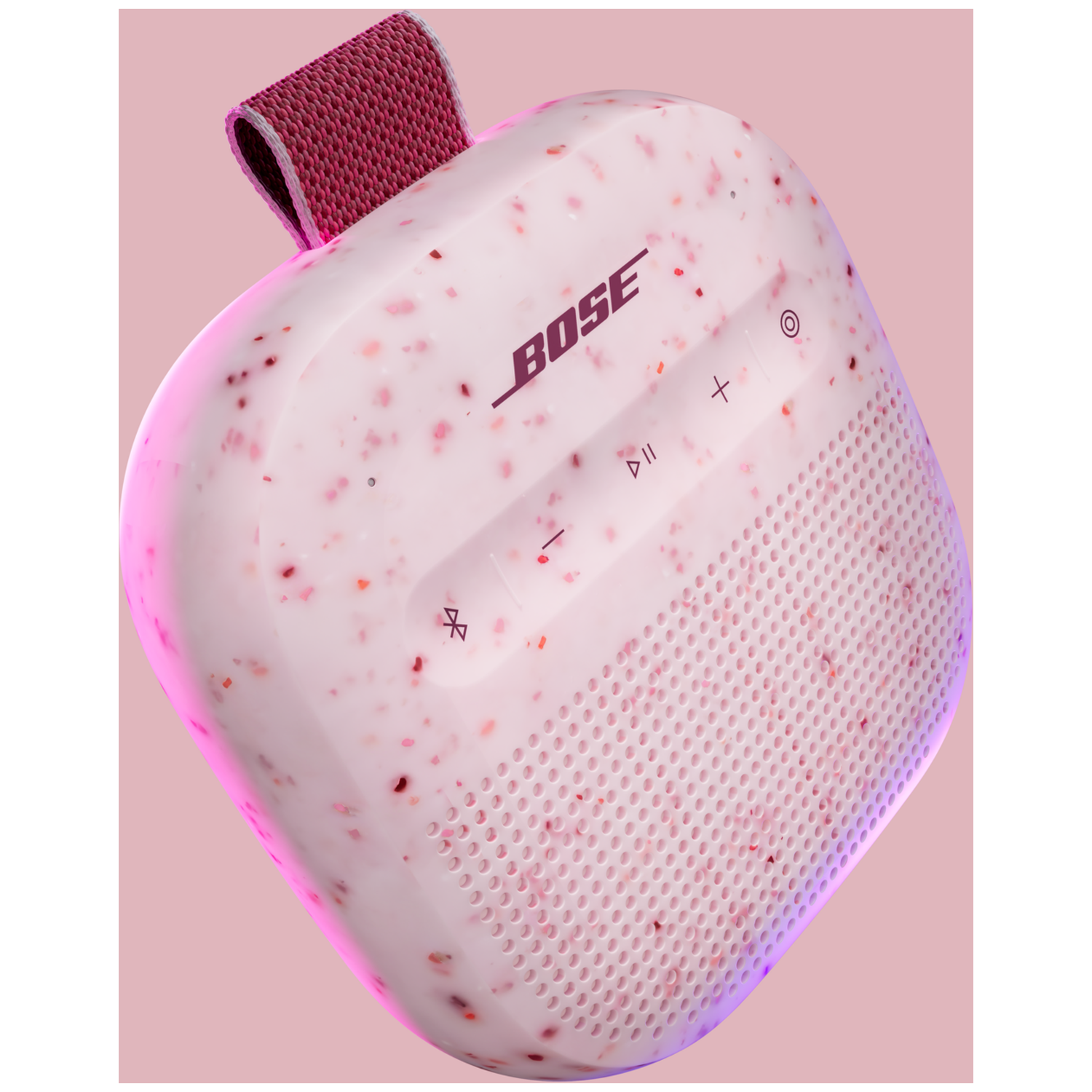 Een roze Bose luidspreker met gespikkeld patroon en rode lus.
