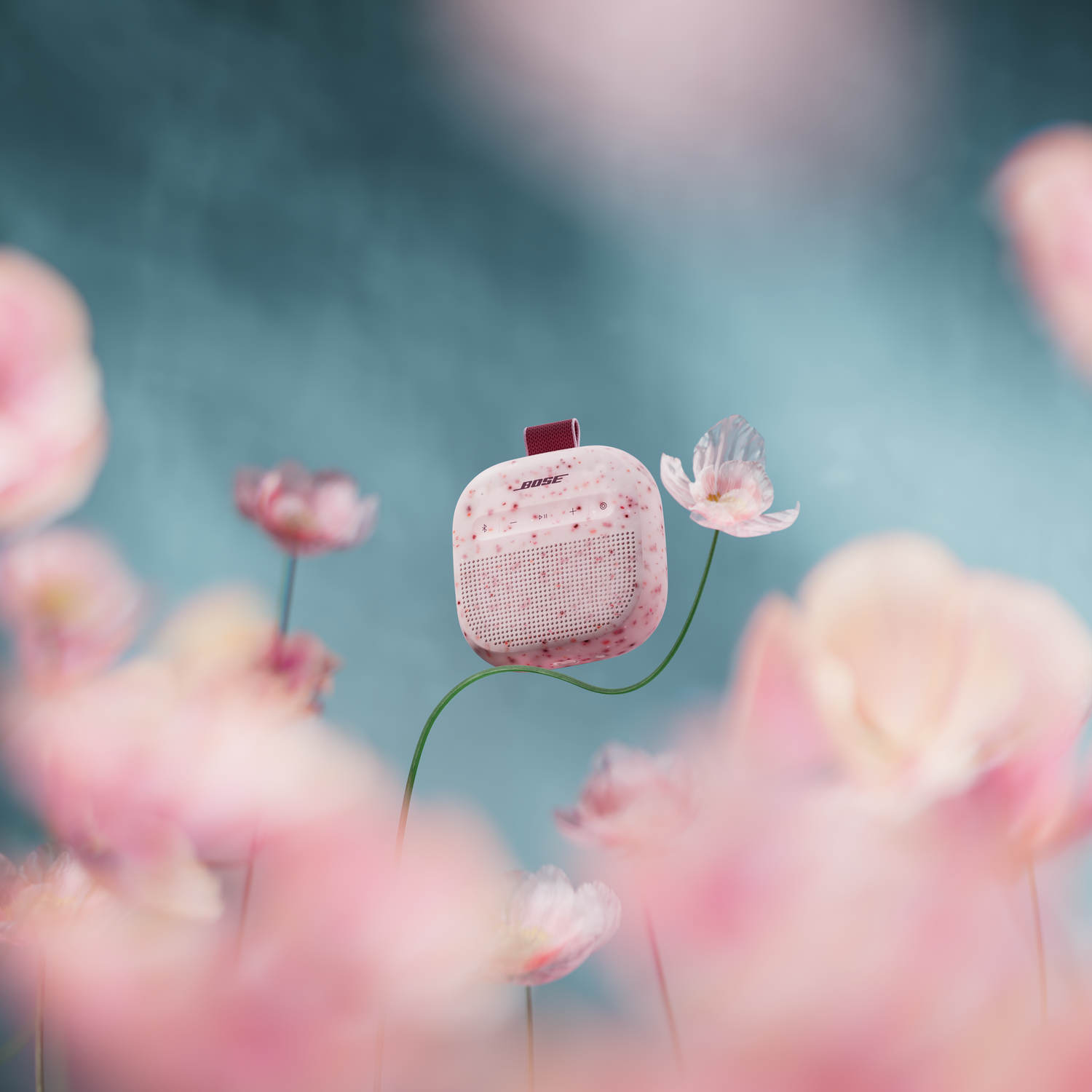 Een roze Bose speaker zweeft boven een veld met roze en blauwe bloemen.