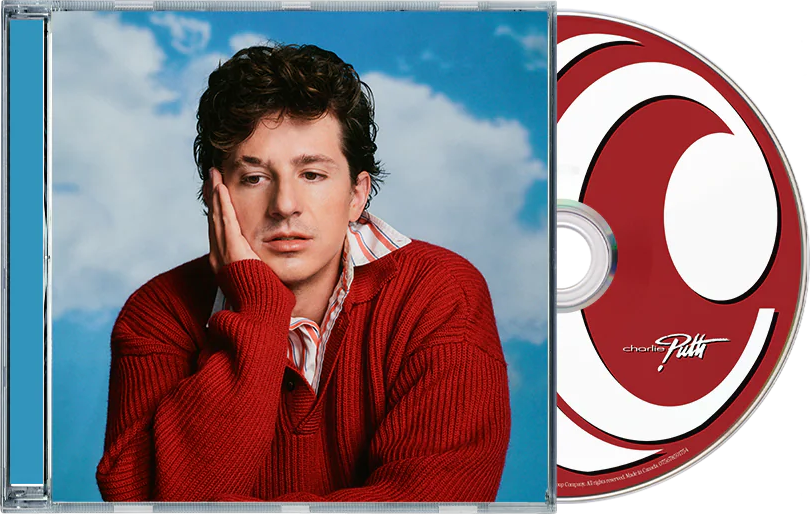 Férfi piros pulóverben és csíkos ingben, kéz az állon, kék felhős ég előtt. Mellette CD.