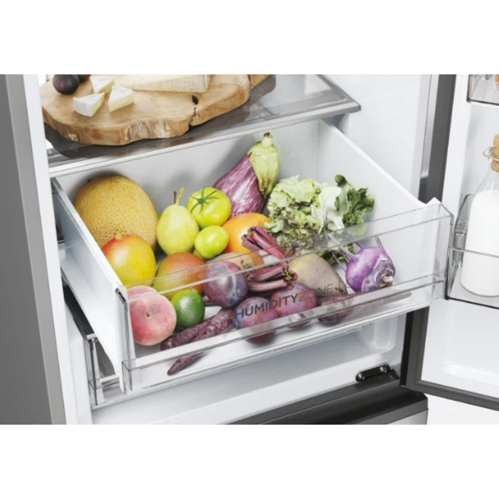 Un cajón de refrigerador lleno de frutas y verduras como melón, berenjena, remolacha y lechuga.