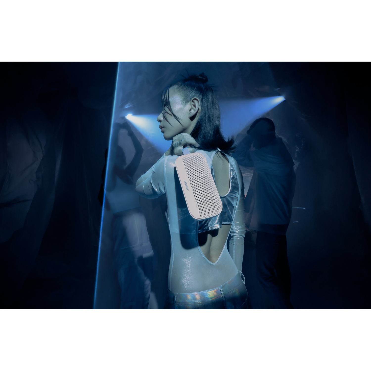 Vrouw in futuristische kleding draagt een witte luidspreker op haar schouder.