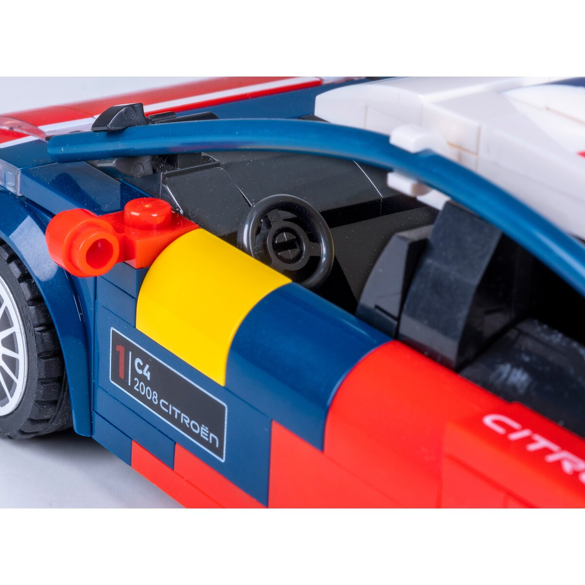Kék Lego versenyautó piros és sárga díszítéssel, kormánykerékkel és "2008 CITROEN" matricával.
