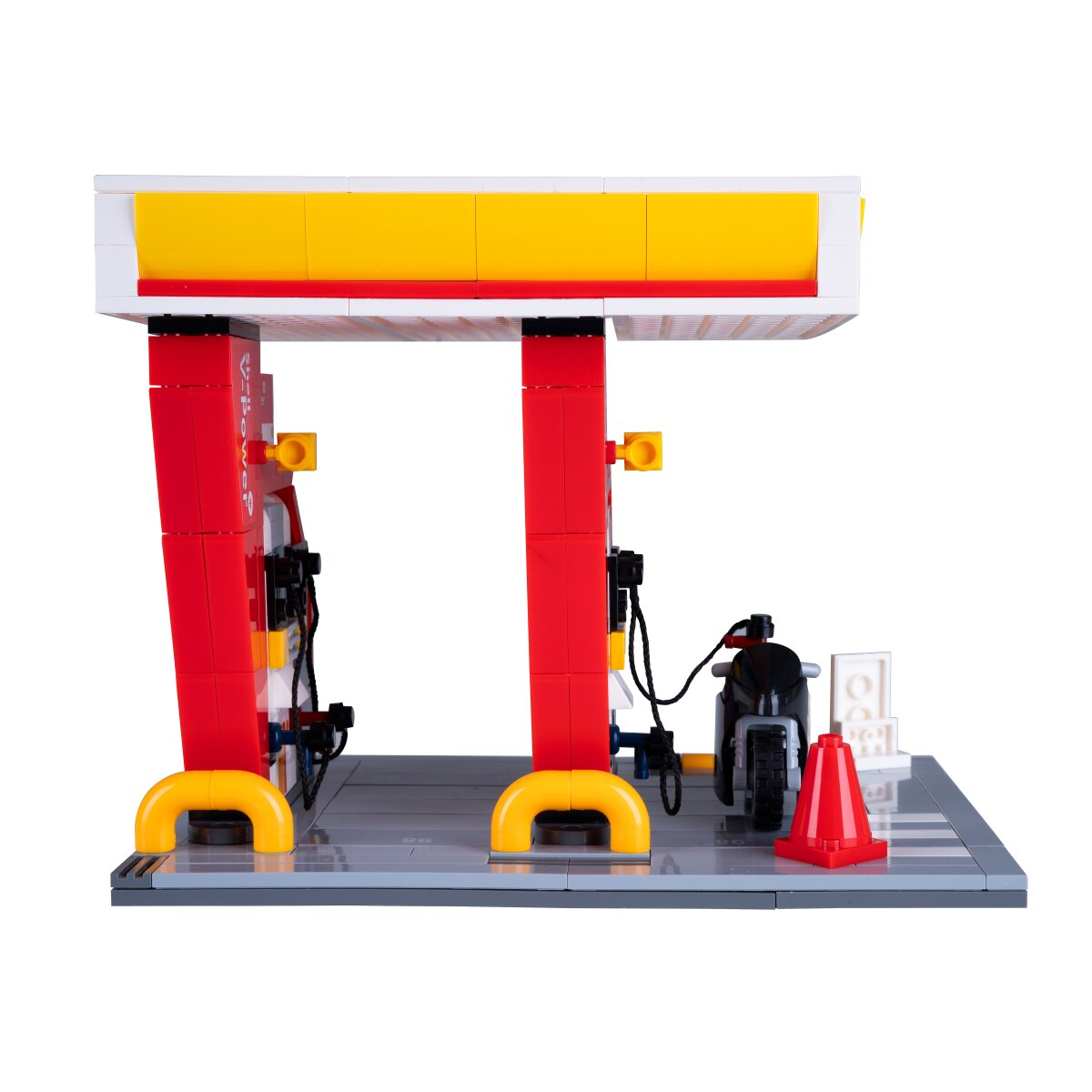 Lego benzinkút piros kutakkal, sárga díszítéssel, motorral és közlekedési kúppal.