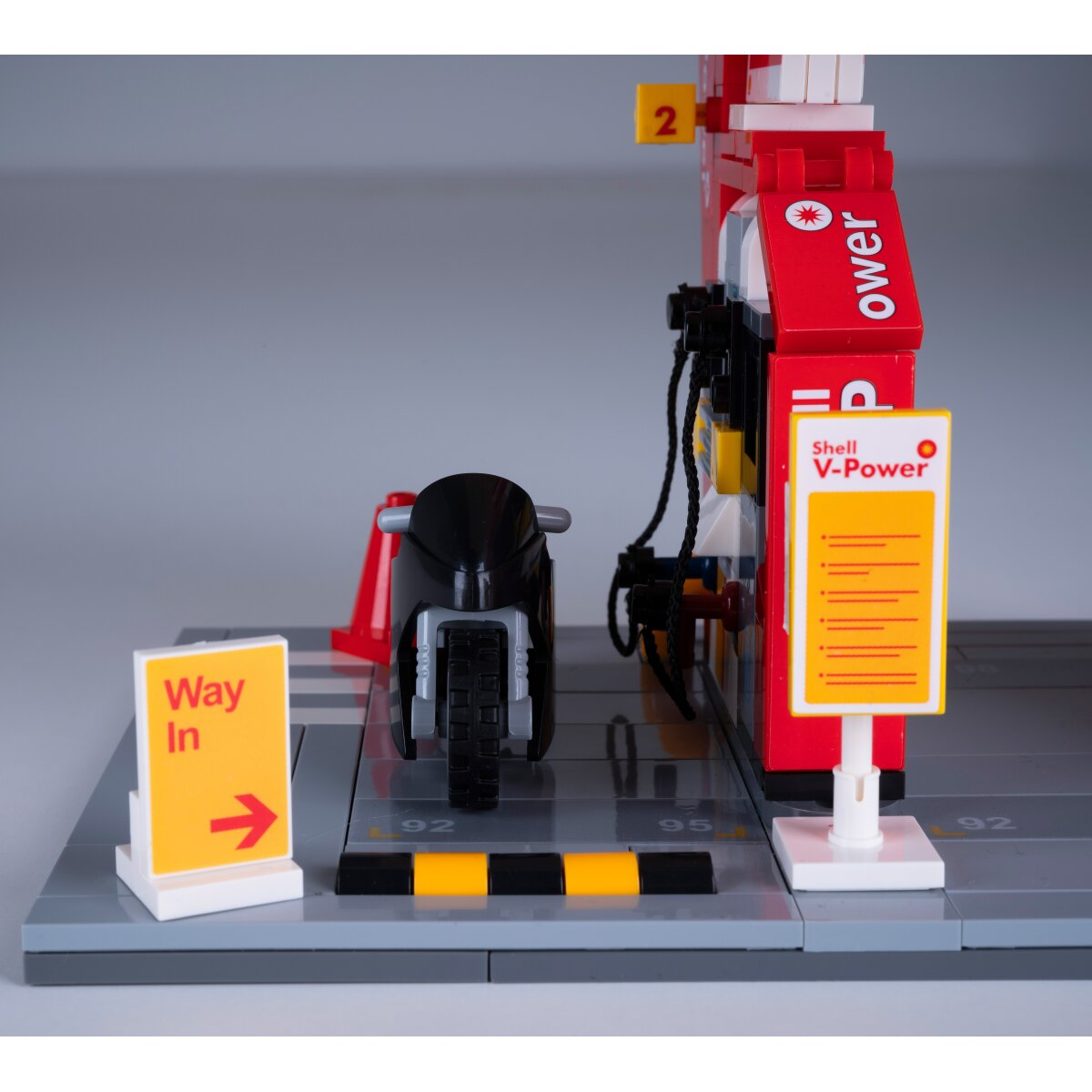 Egy motorkerékpár egy Lego benzinkúton, Shell V-Power felirattal és Bejárat táblával.