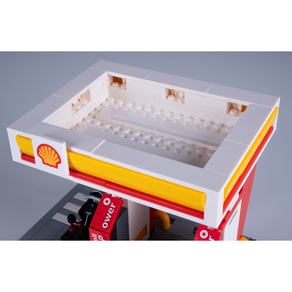 Egy Lego Shell benzinkút modell sárga és piros díszítéssel.