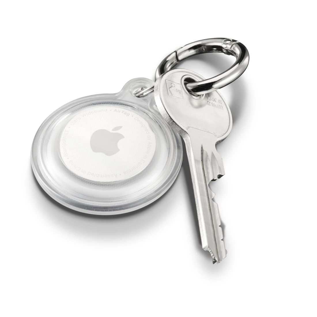 Ein runder Apple AirTag in einer durchsichtigen Hülle neben einem silbernen Schlüssel.