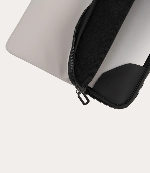 Funda gris para portátil con cremallera negra, parcialmente abierta.