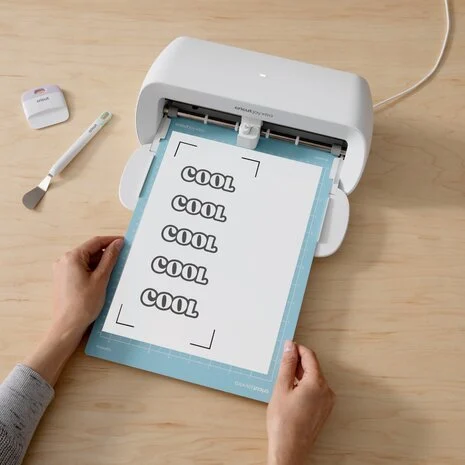 Una persona usando una máquina Cricut Joy Xtra con una alfombrilla y papel.
