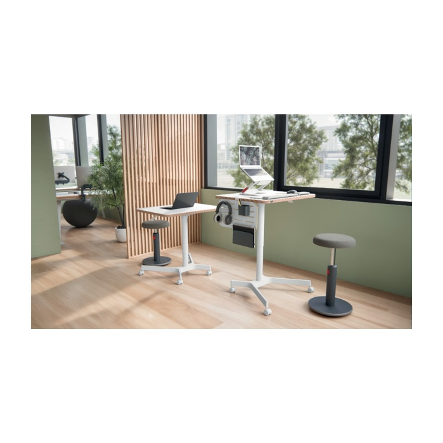Ufficio moderno con scrivanie sit-stand, laptop, cuffie e sgabelli.