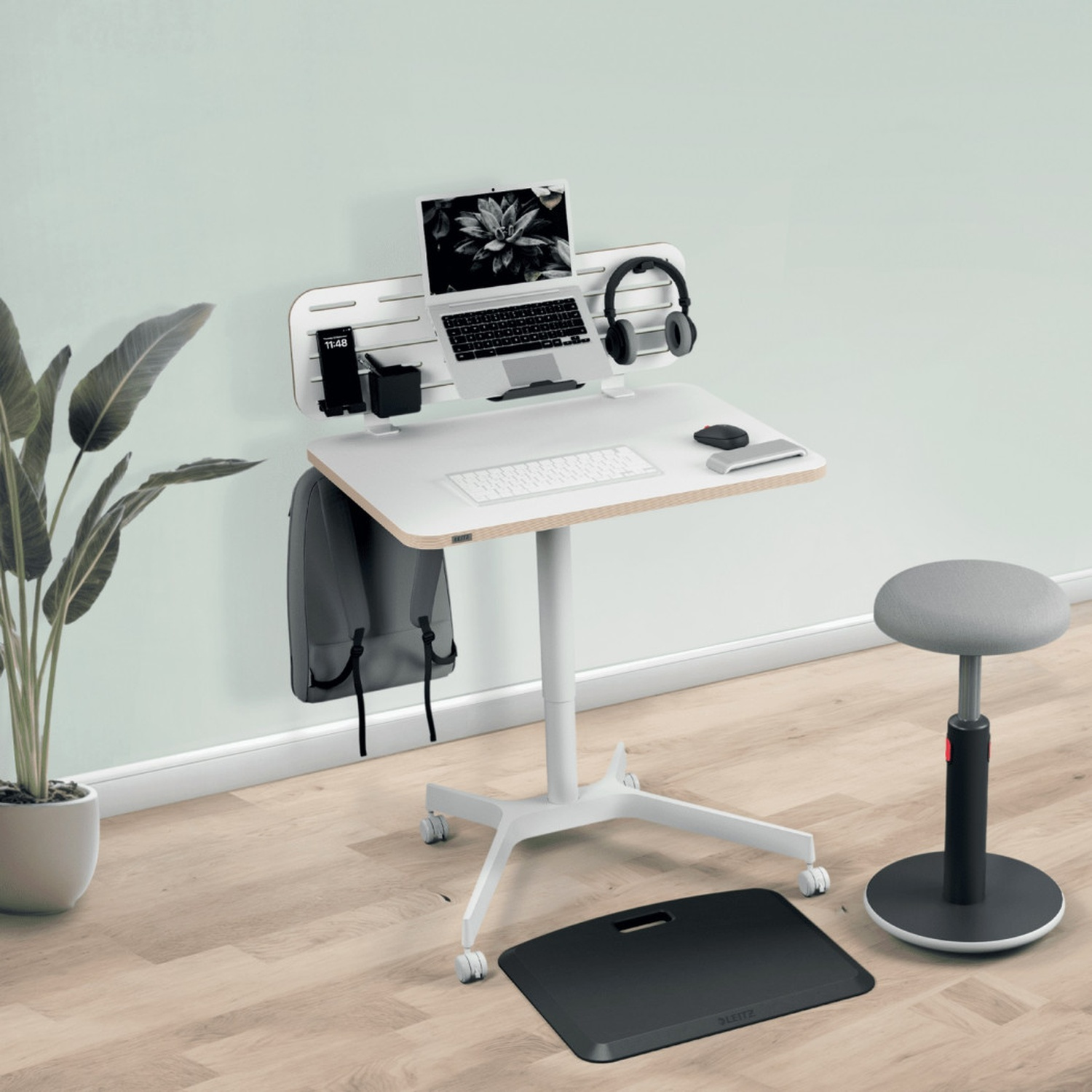 Una scrivania regolabile in altezza con laptop, tastiera, mouse e cuffie.
