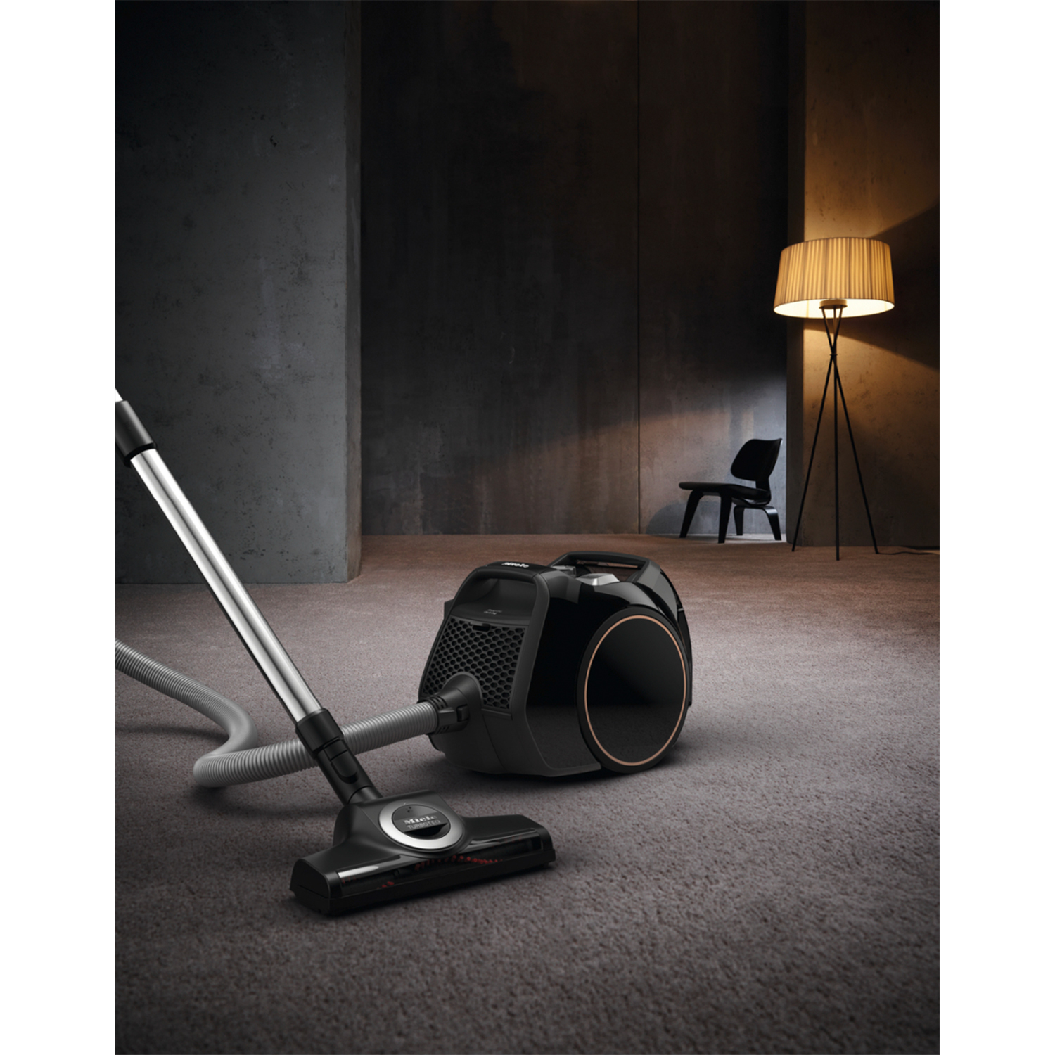 Un aspirapolvere Miele nero con spazzola per pavimenti su un tappeto.