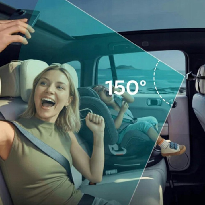 Kobieta robi selfie w samochodzie, dziecko w foteliku. Morze w tle.