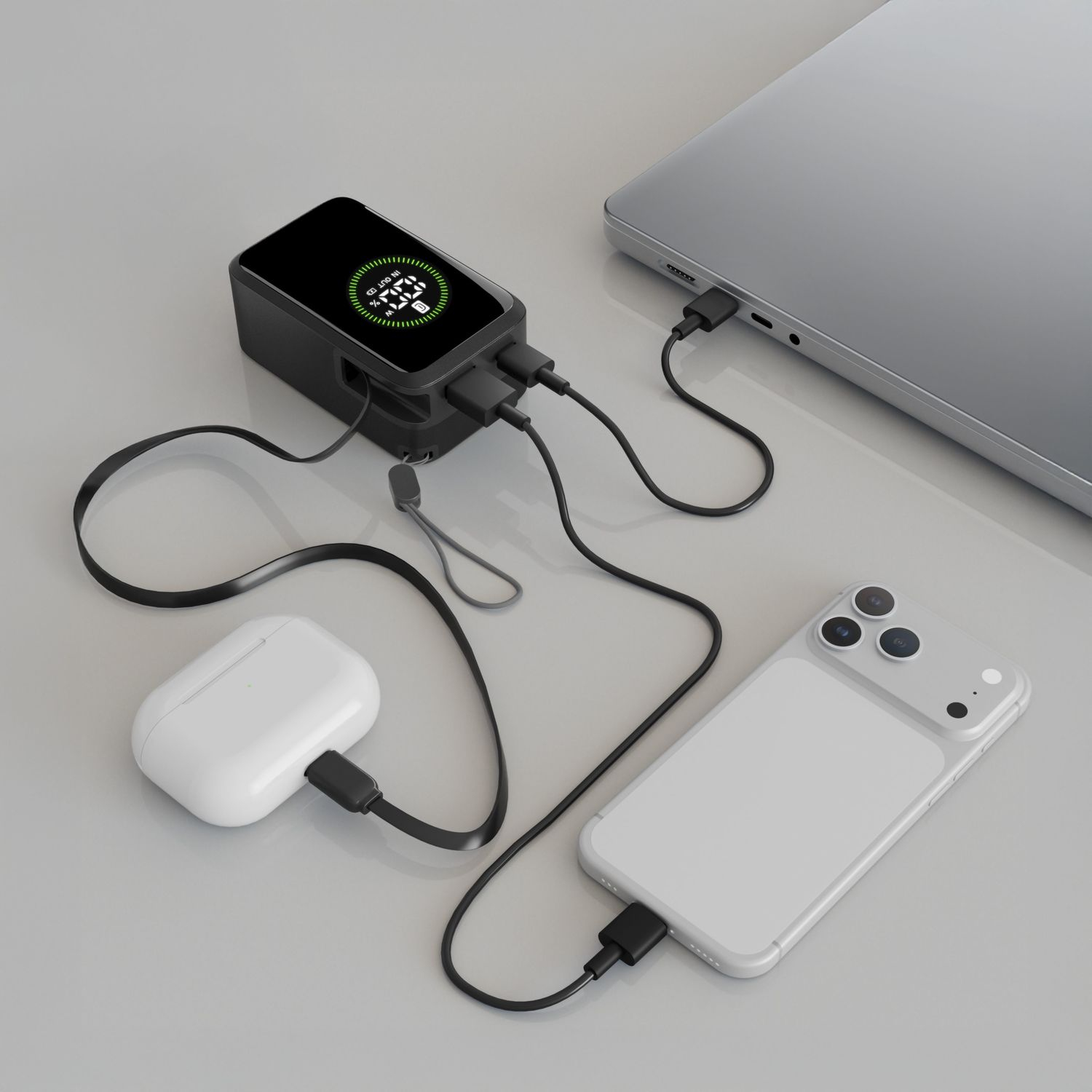 Power bank negra cargando portátil, teléfono y estuche de auriculares.