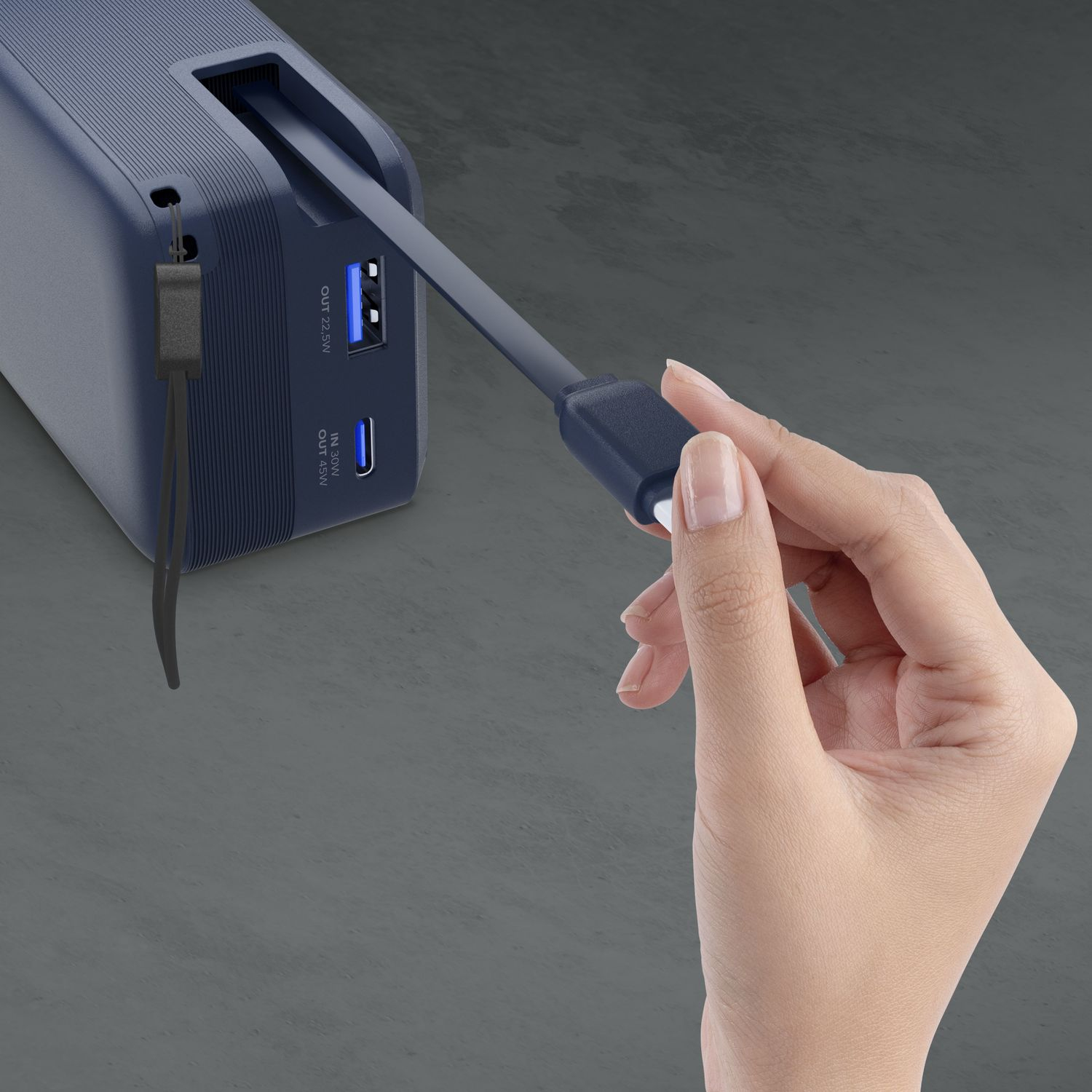 Una mano inserta un cable USB en un banco de energía azul oscuro.