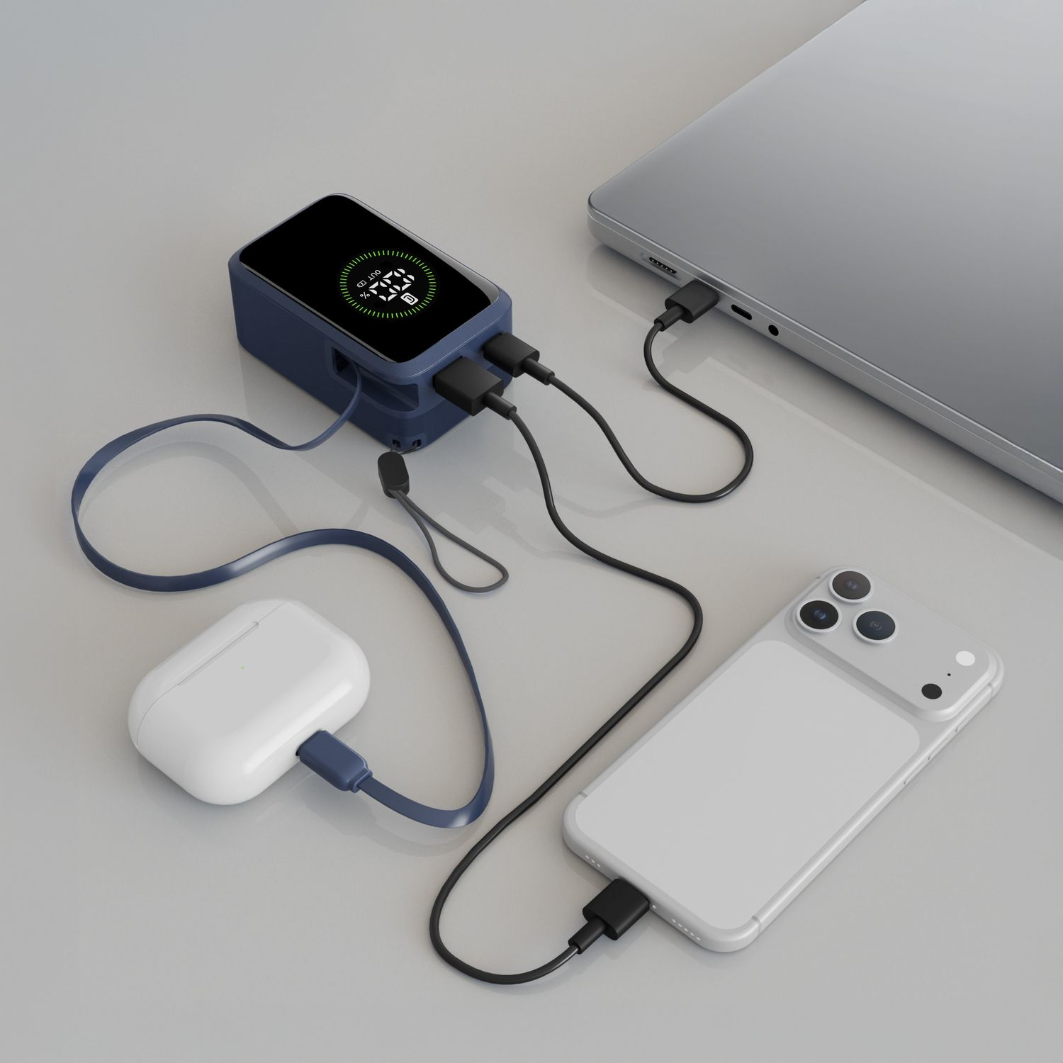 Un banco de energía azul carga un teléfono, estuche de auriculares y portátil con cables.