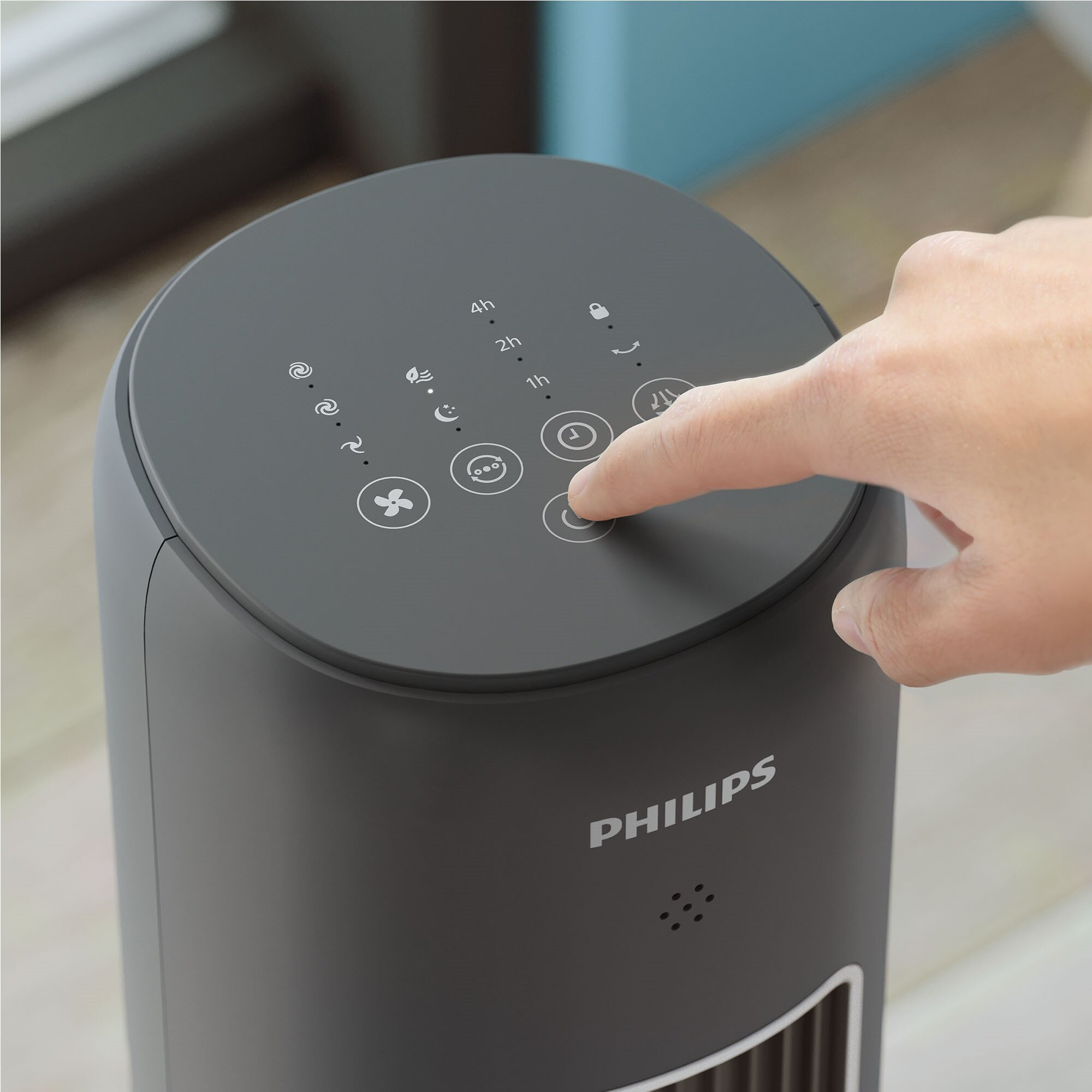 Palec naciska przycisk zasilania szarego wentylatora wieżowego Philips.