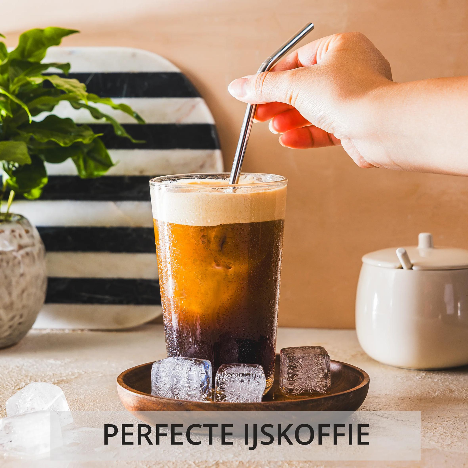 IJskoffie met ijsklontjes, een rietje en een suikerpot.