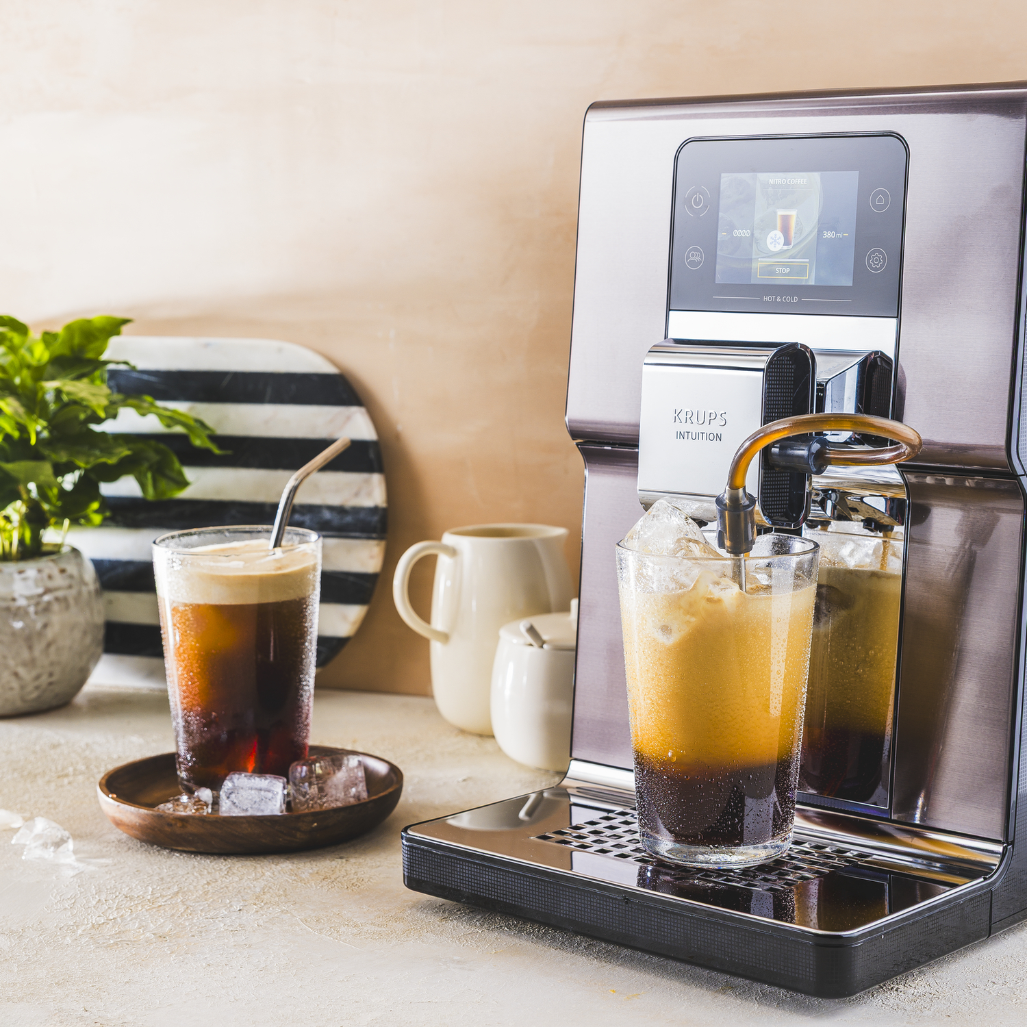 Koffiezetapparaat bereidt dranken, twee glazen met ijs en koffie staan klaar.
