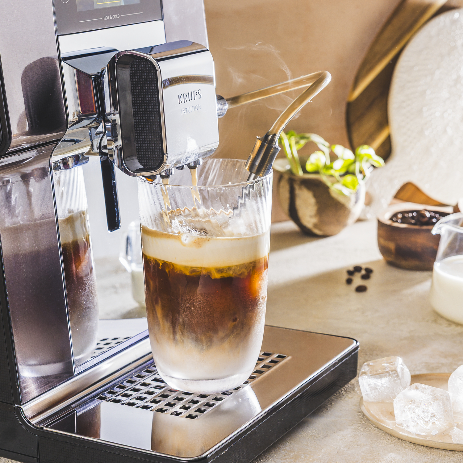 Koffiezetapparaat brouwt ijsthee in een glas met melkschuim. Stoom stijgt op.