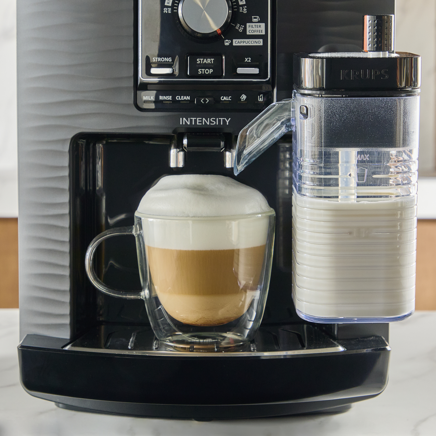 A coffee machine with a glass of latte and a milk container.
