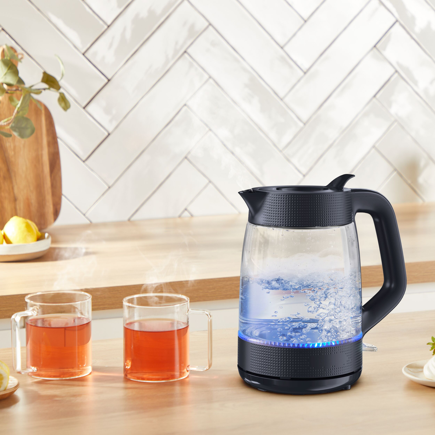 Een waterkoker kookt water, met dampende kopjes thee ernaast.
