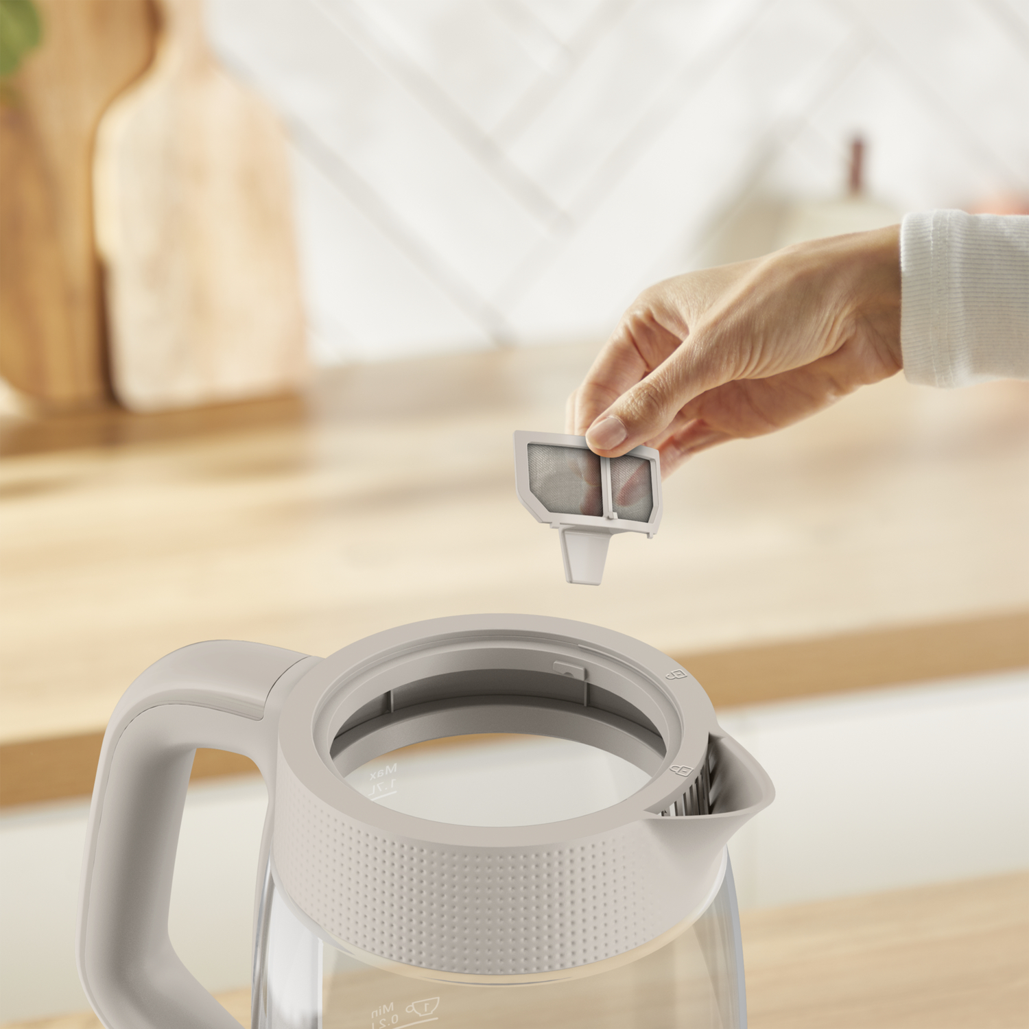 A hand holds a filter over an open kettle.