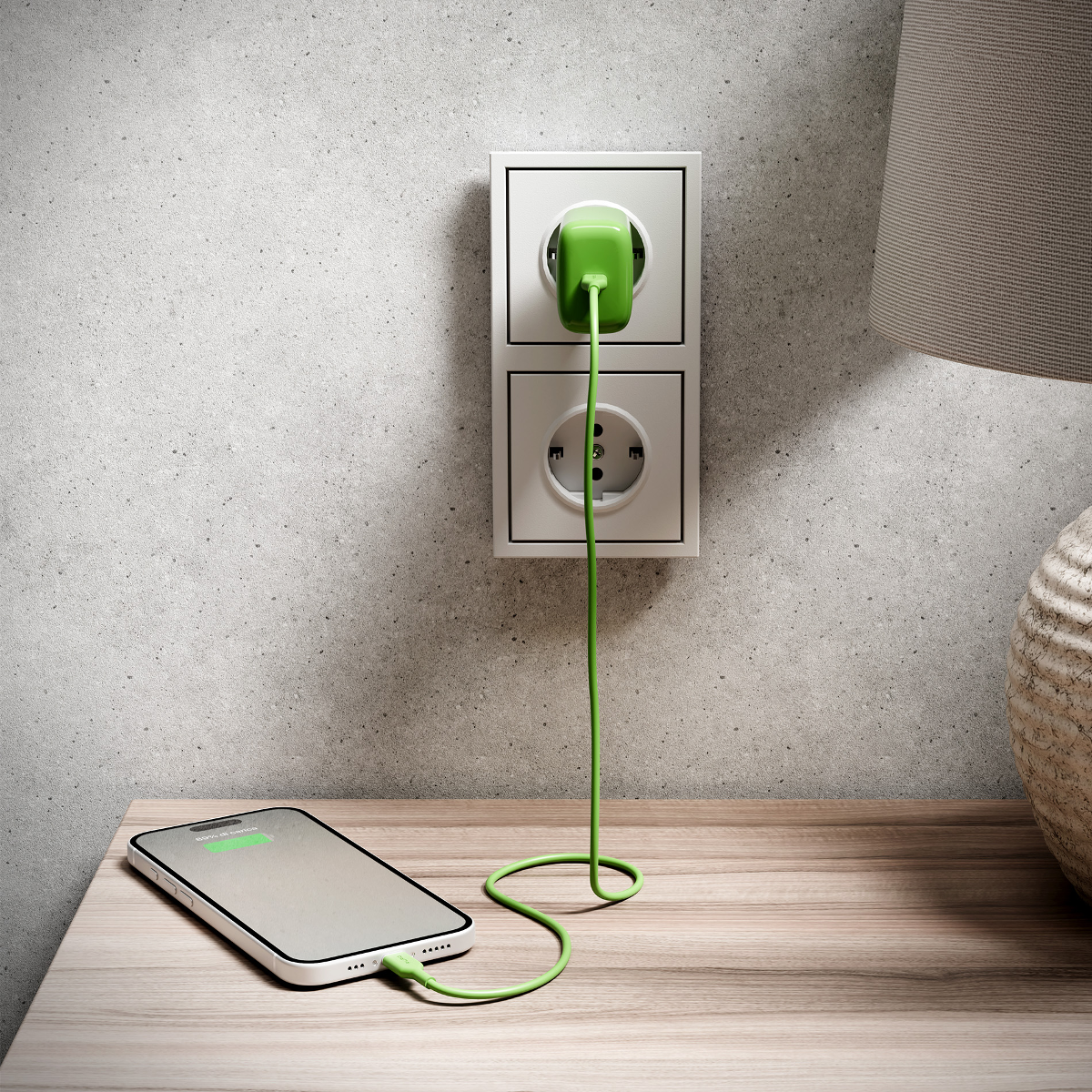 Ein grüner Stecker ist in eine Steckdose gesteckt und lädt ein Handy.