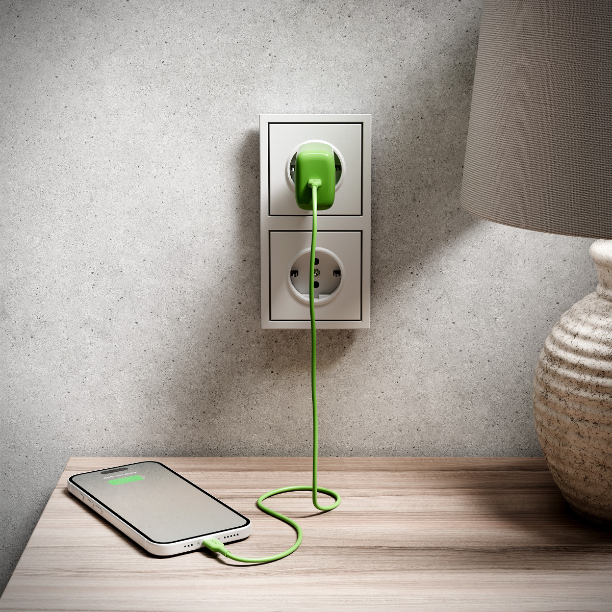 Ein grüner Stecker ist in eine Steckdose gesteckt, ein Kabel lädt ein Handy.