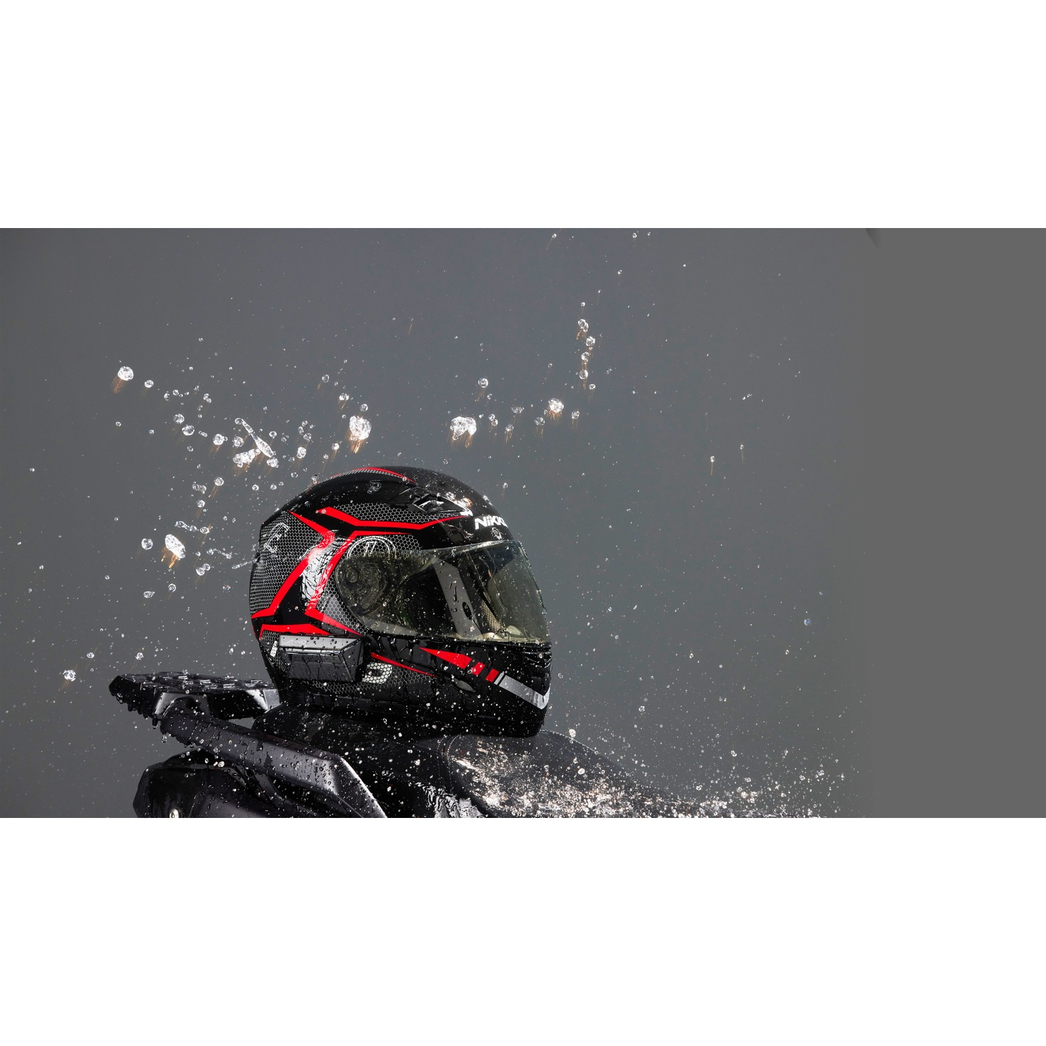 Een zwarte helm met rode accenten wordt besproeid met water.