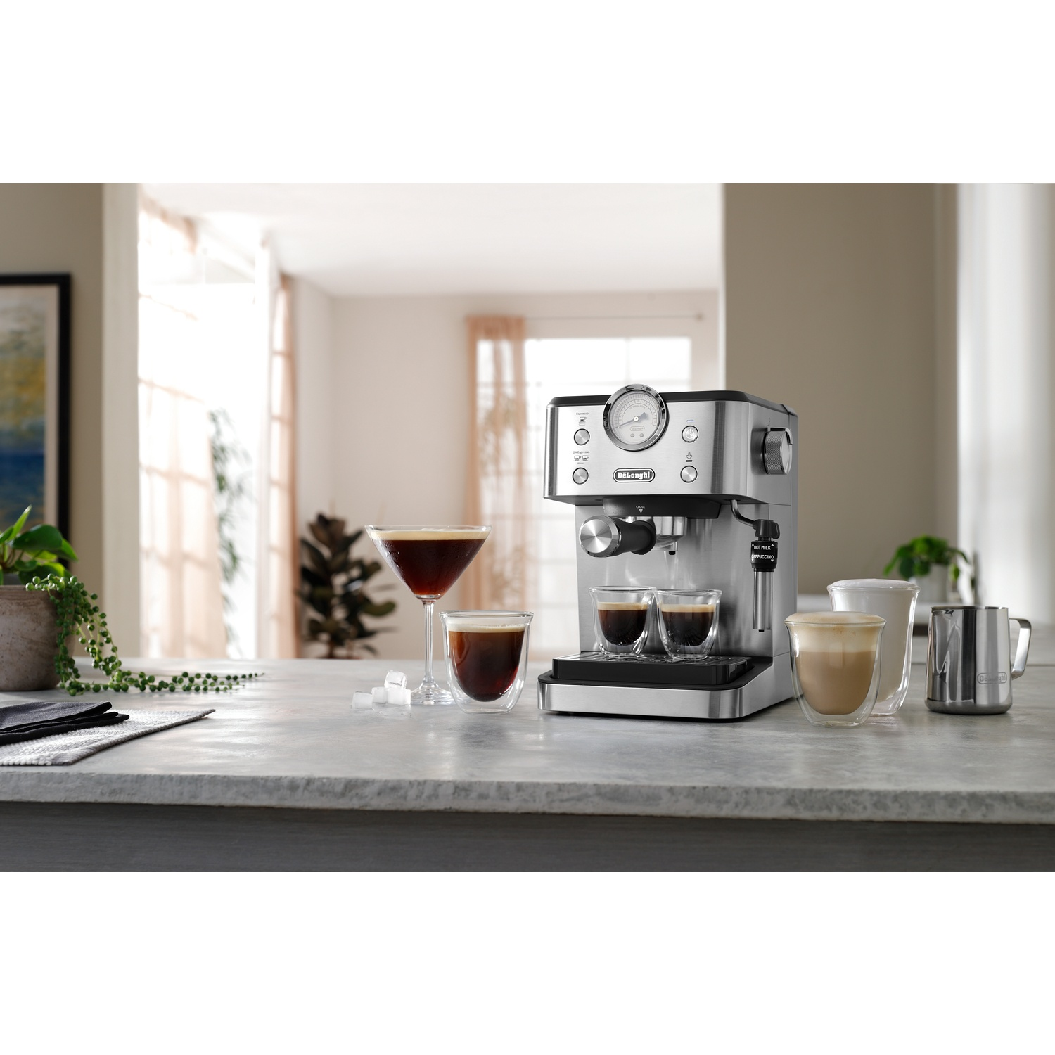 A silver espresso machine on a stone counter with two espressos and a martini glass.