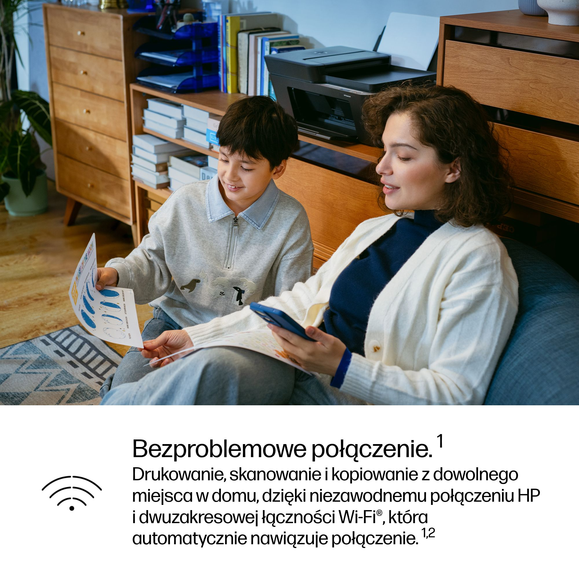 Kobieta i dziecko siedzą na kanapie, patrzą na papier. Drukarka w tle.