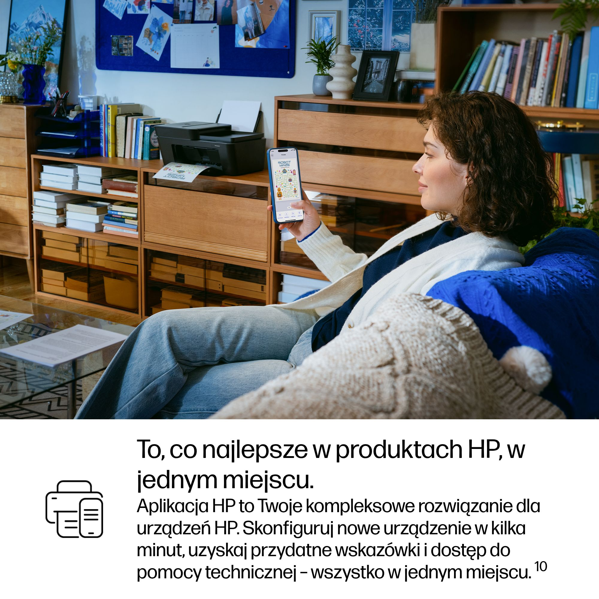 Kobieta trzyma smartfon z aplikacją. Drukarka stoi na półce.