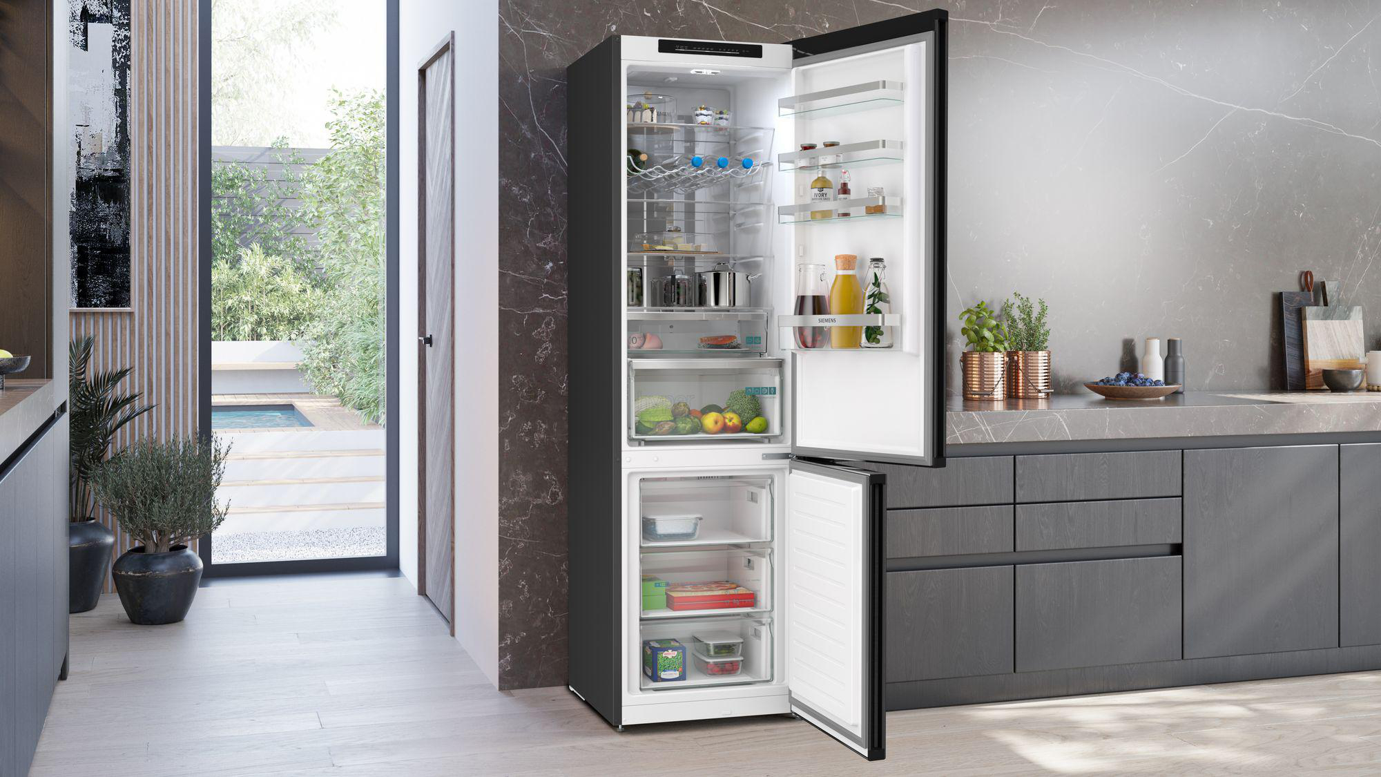 Offener schwarzer Kühlschrank mit Lebensmitteln und Blick nach draußen auf einen Garten.