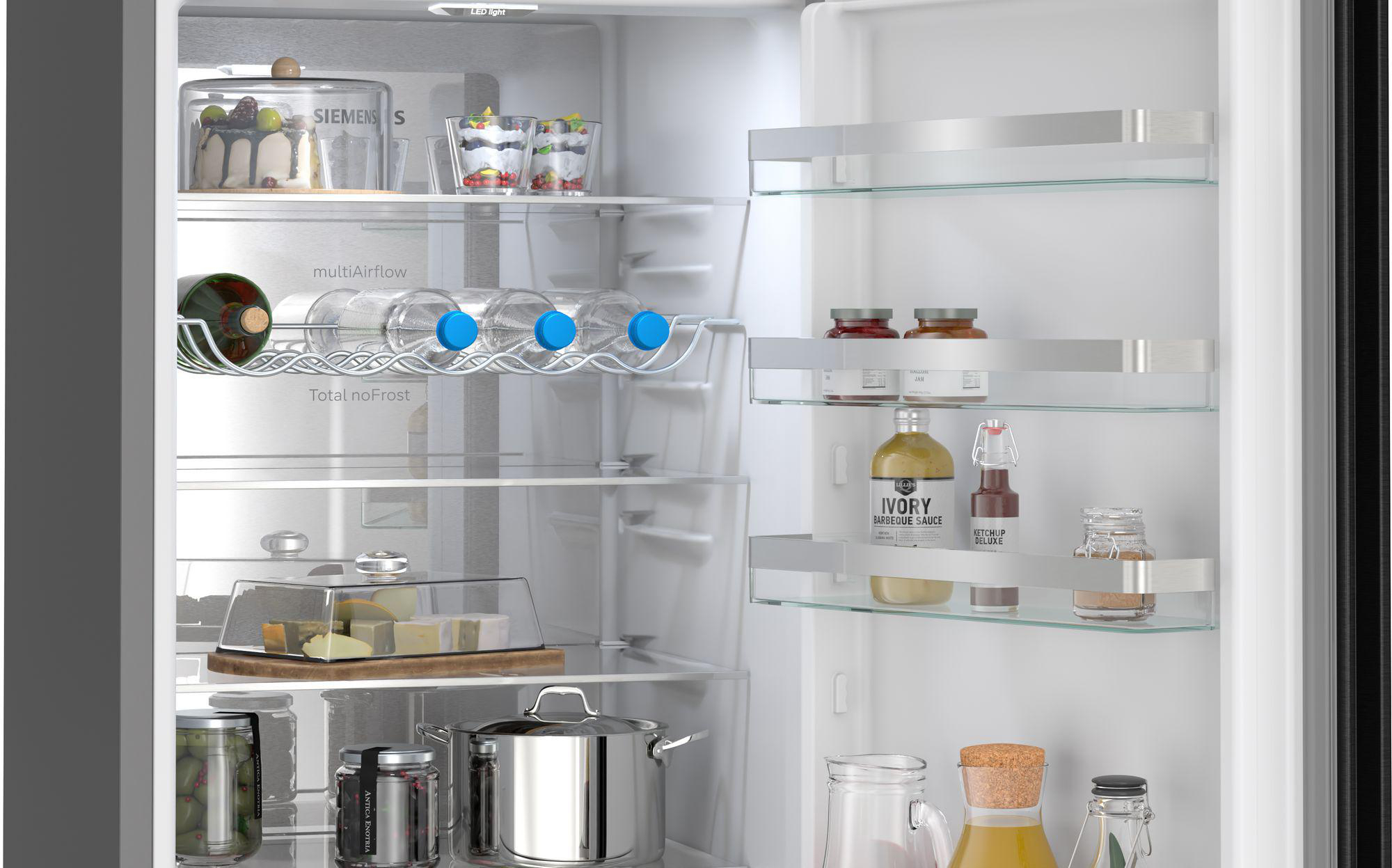 Offener Kühlschrank mit Kuchen, Desserts, Flaschen, Käse, Gläsern und Töpfen.