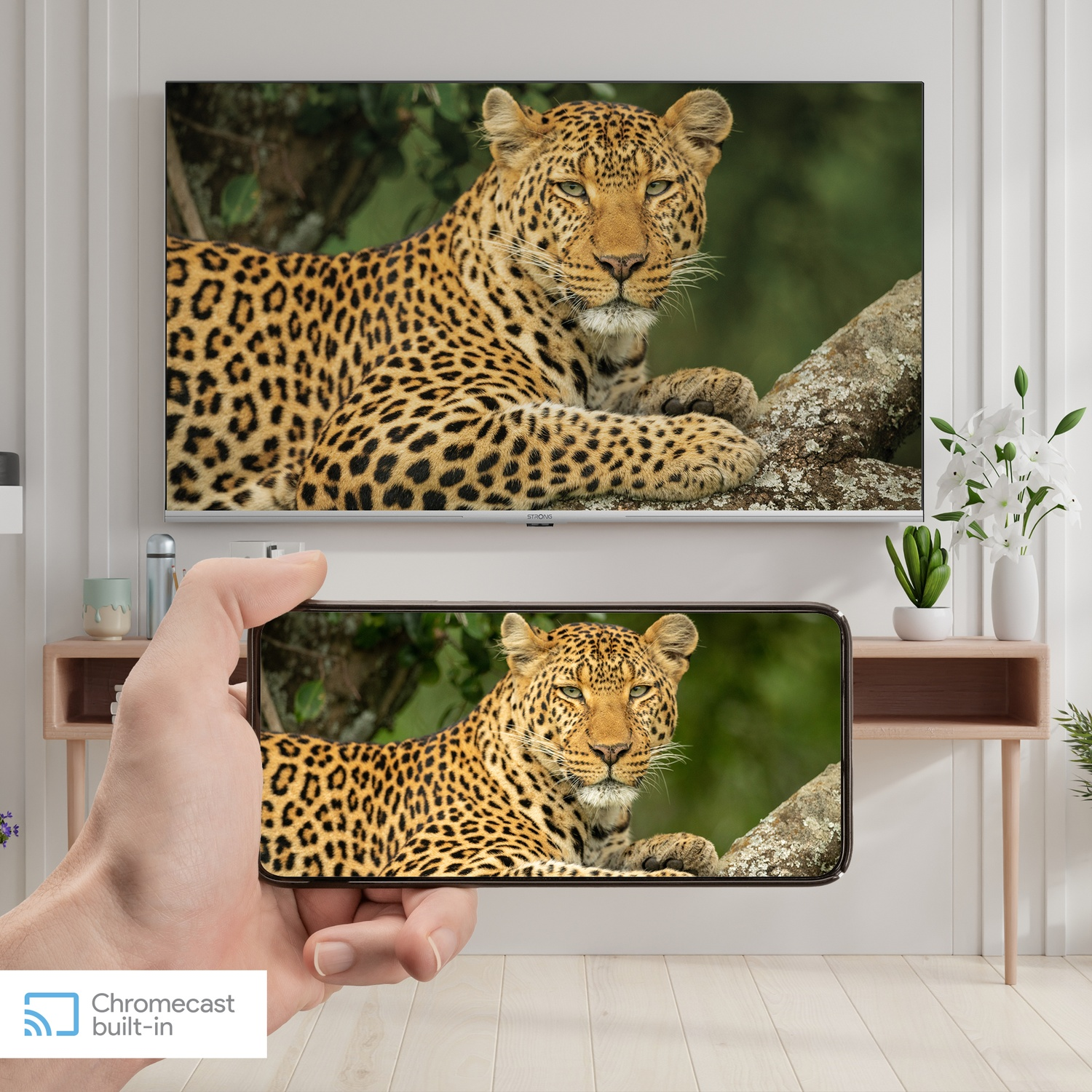 Un leopardo riposa su un ramo, con un telefono che mostra la stessa immagine.