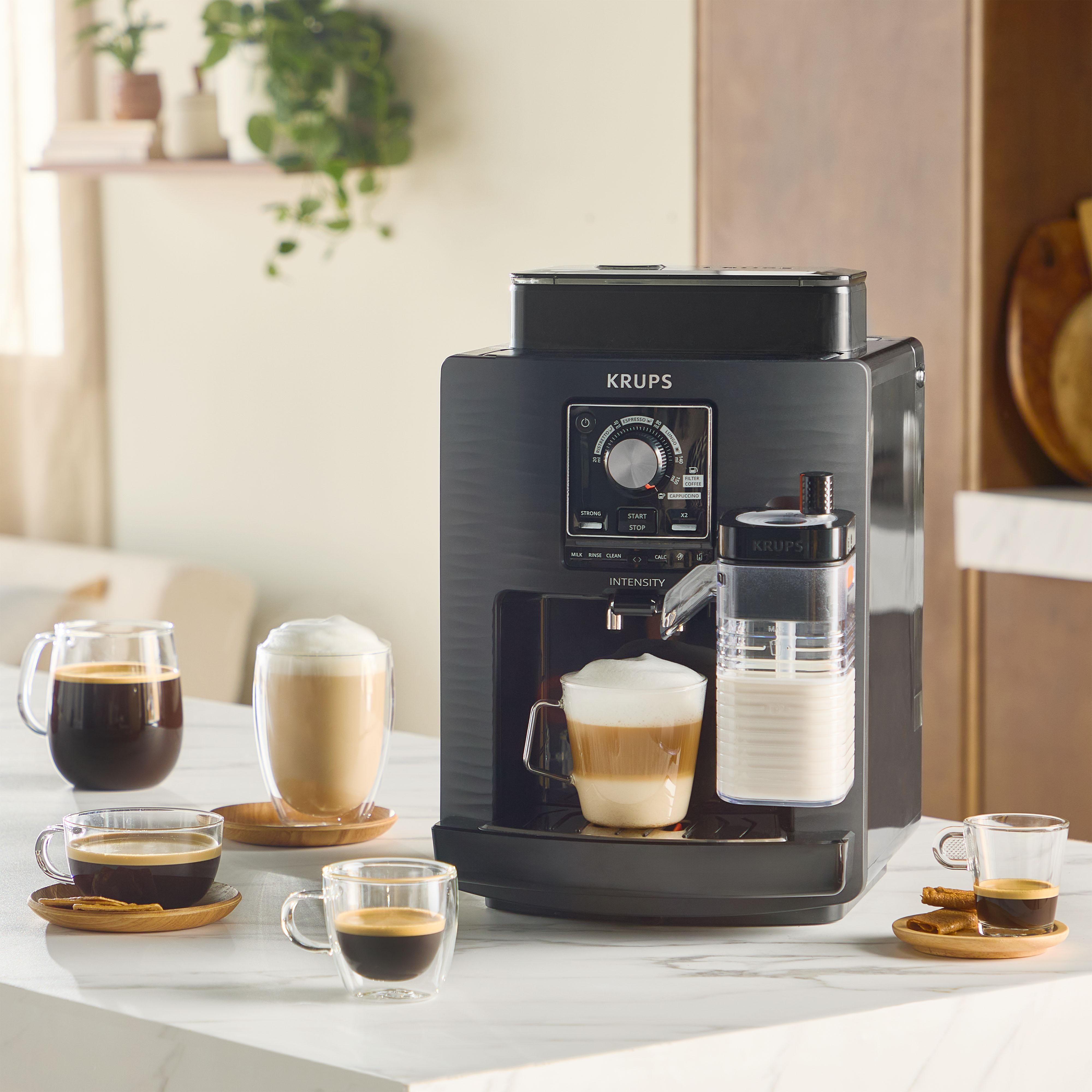 Eine schwarze Krups Kaffeemaschine mit Milchtank und mehreren Tassen Kaffee.