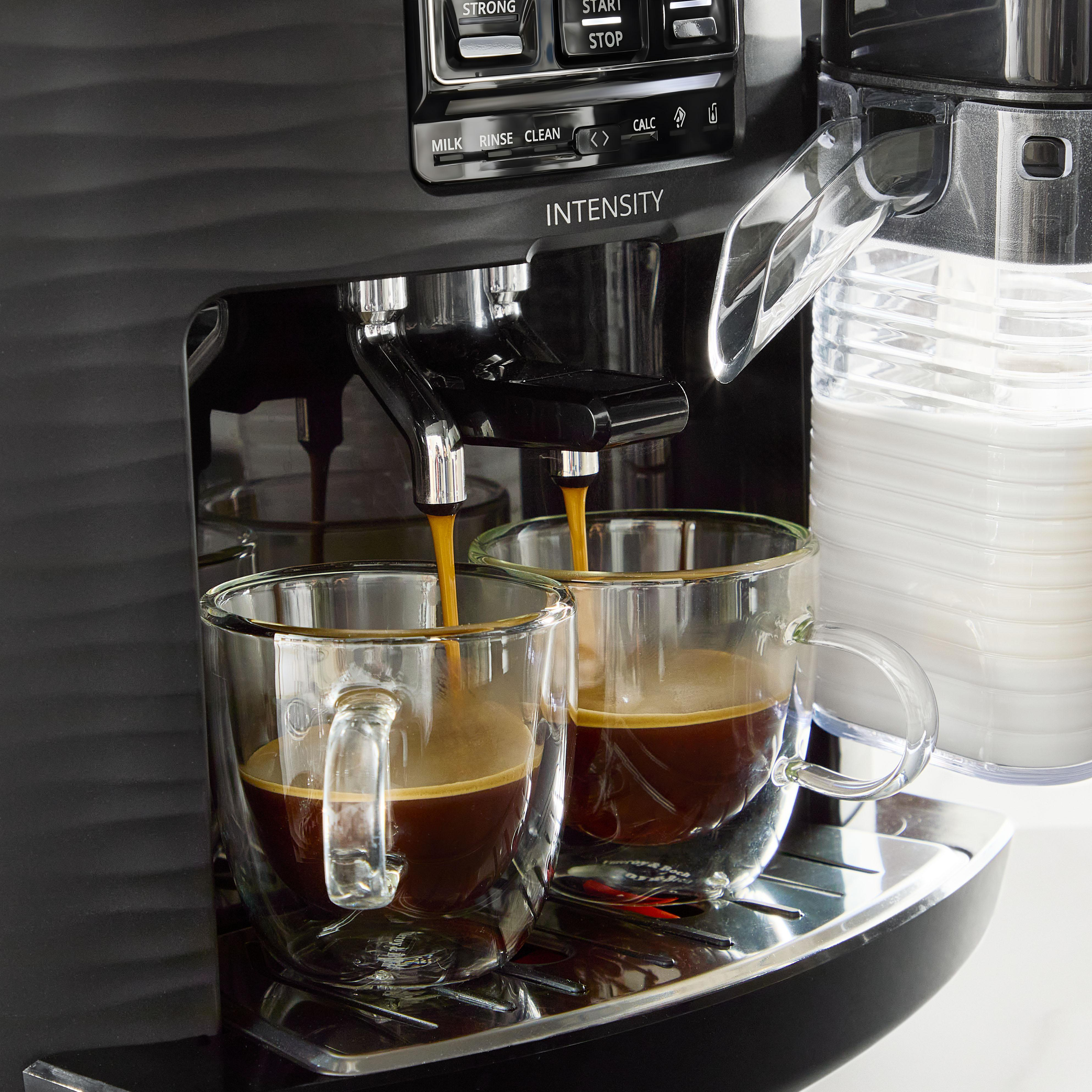 Kaffee fließt in zwei Gläser von einer Kaffeemaschine. Milchbehälter daneben.