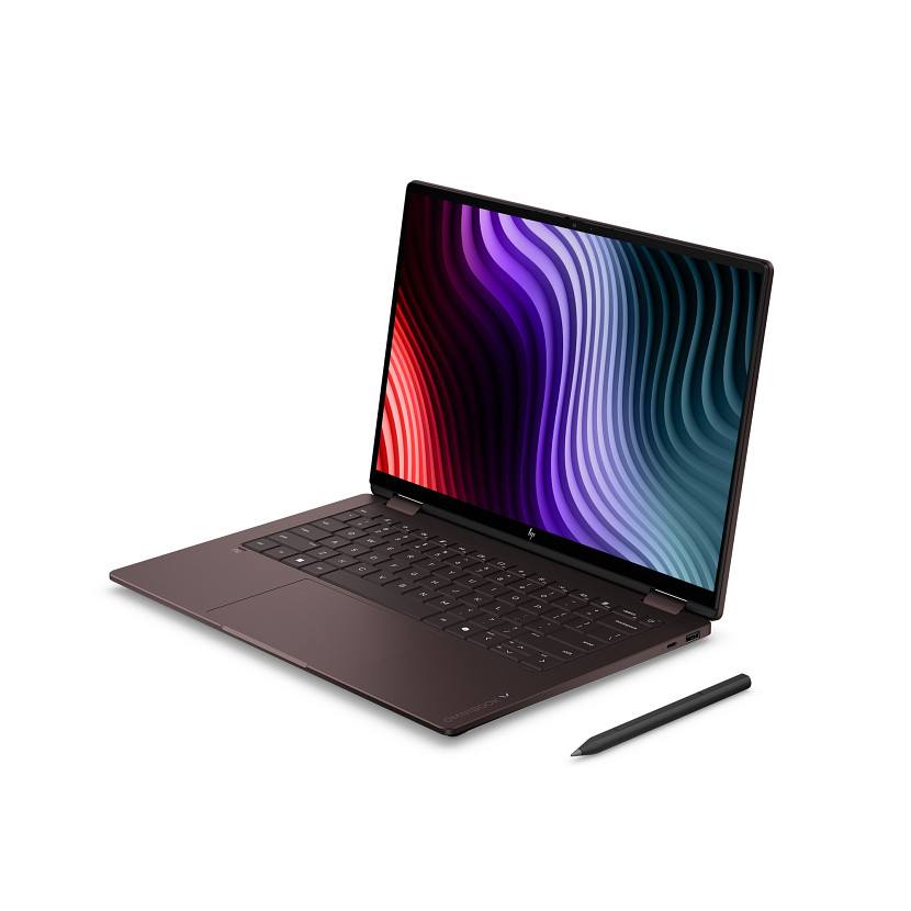 Otwarty, ciemnobrązowy laptop z kolorową tapetą i piórkiem obok.