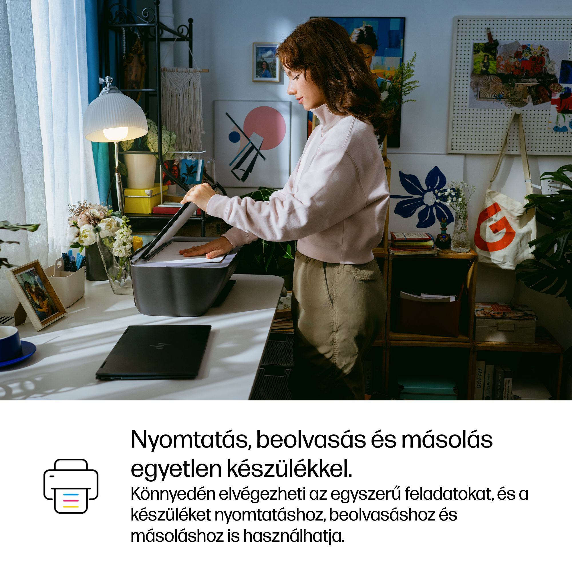 Egy nő egy nyomtatót nyit ki egy asztalon, mellette egy laptop.