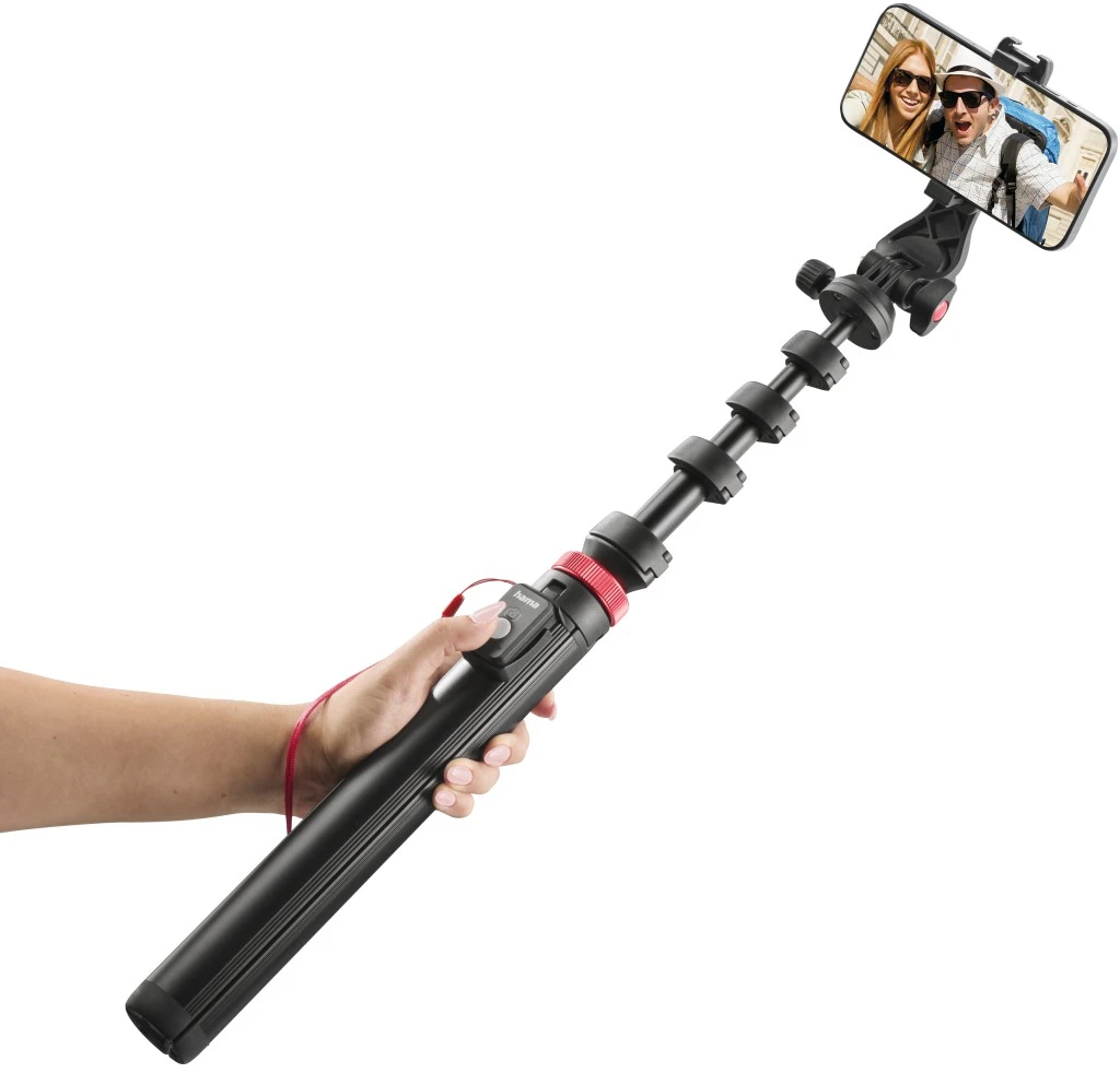Una mano tiene un selfie stick nero con braccio telescopico esteso e uno smartphone.