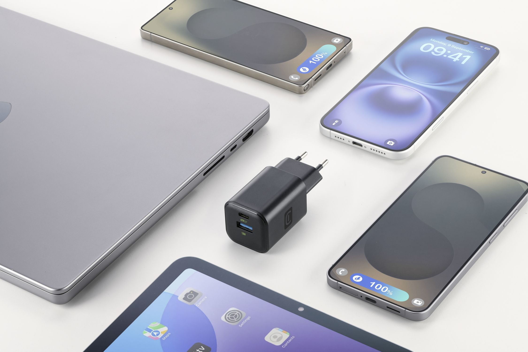 Un portátil, cargador, tableta y tres teléfonos inteligentes sobre fondo blanco.