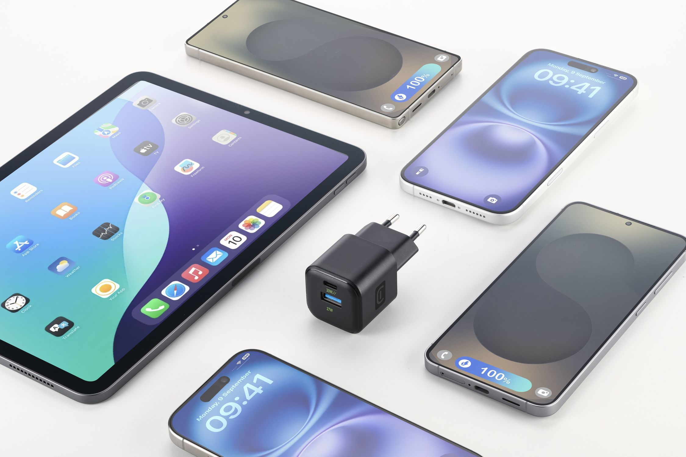 Una tableta, tres teléfonos inteligentes y un cargador sobre fondo blanco.